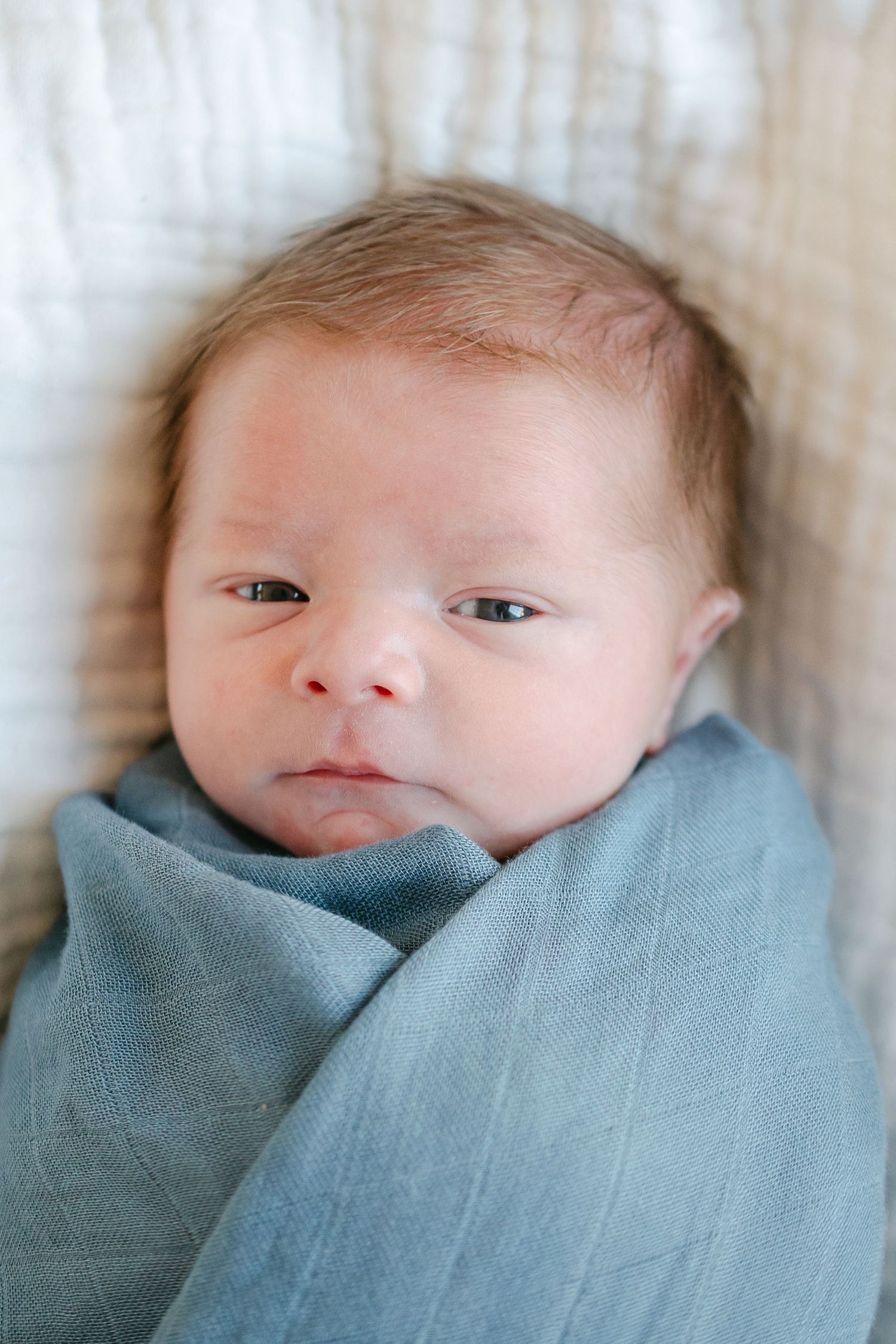 Close-up shots of a newborn baby wrapped in a soft blue swaddle blanket.
