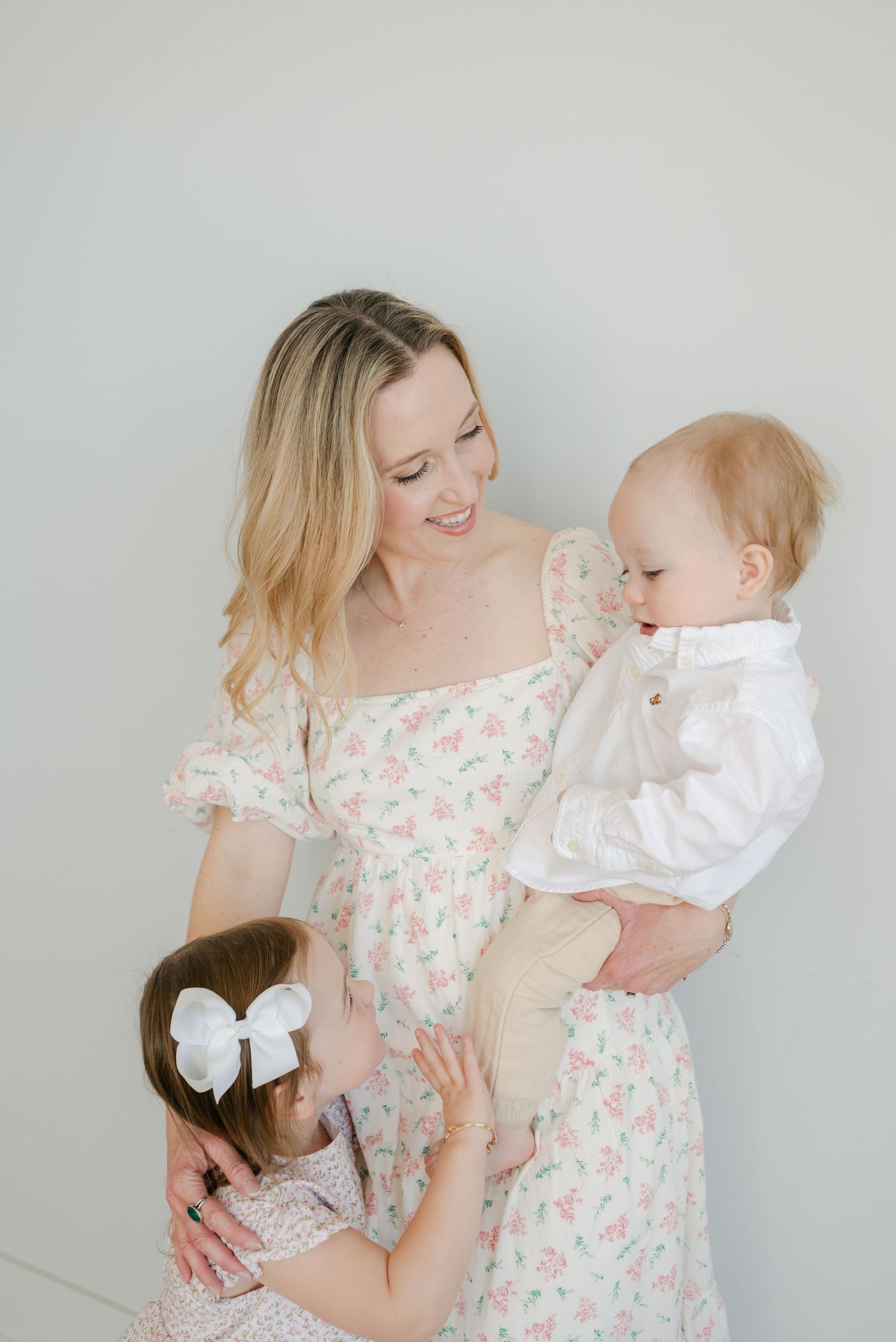 A tender moment captured in a series of photos showing a parent and baby in matching floral dresses against a white backdrop.