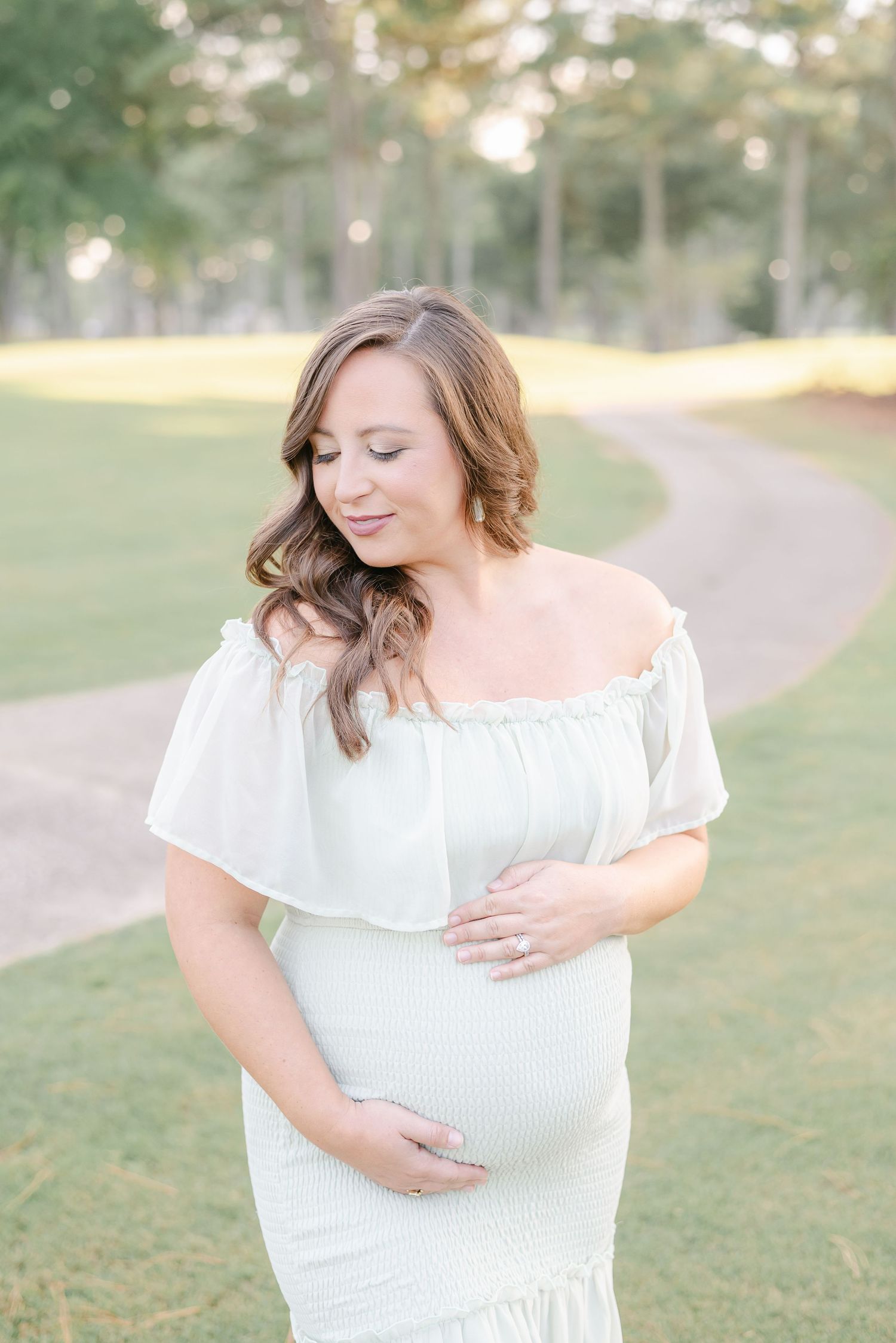 Maternity portraits taken in a park setting with soft natural lighting.