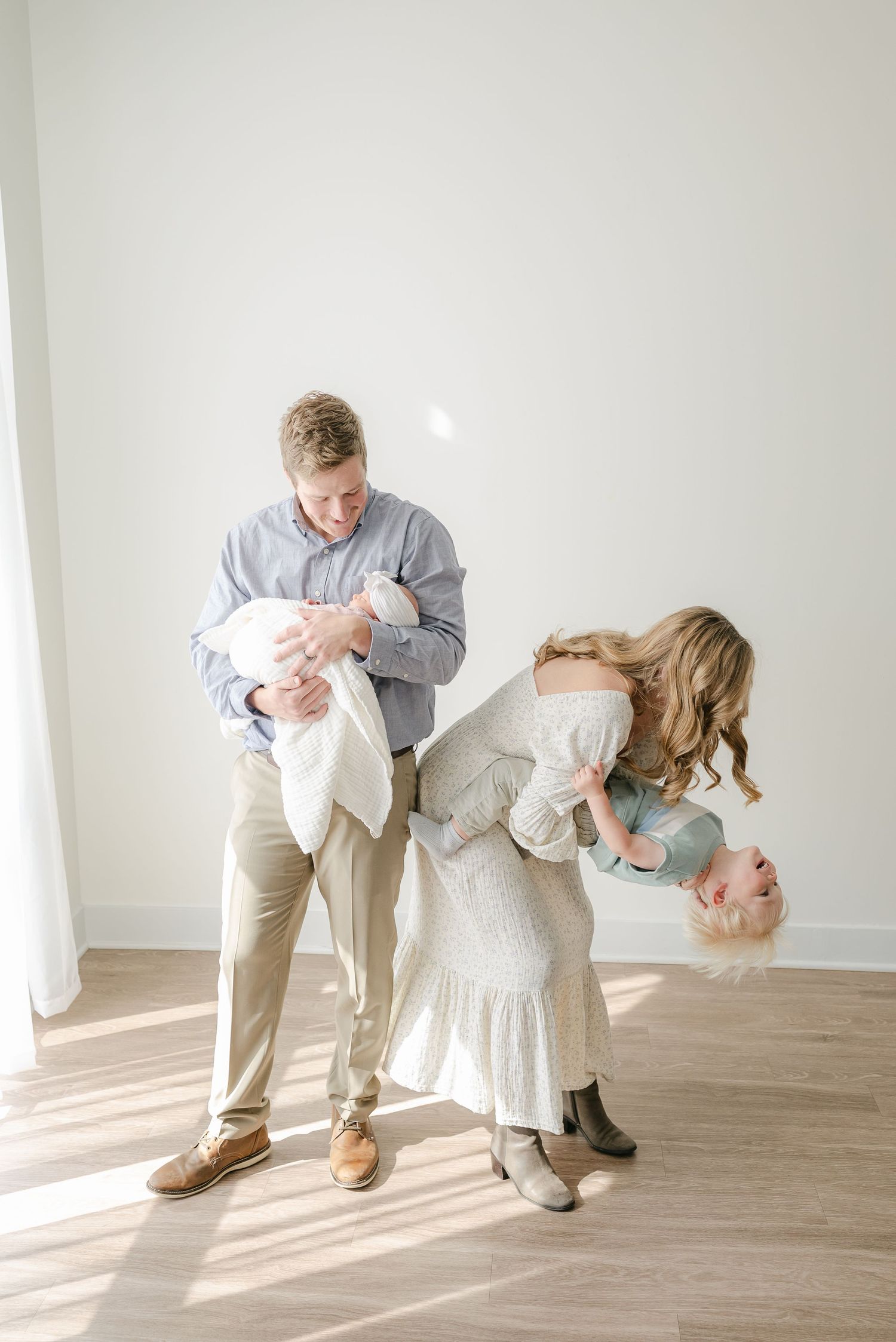 Playful family photo session with joyful interactions on hardwood floor.