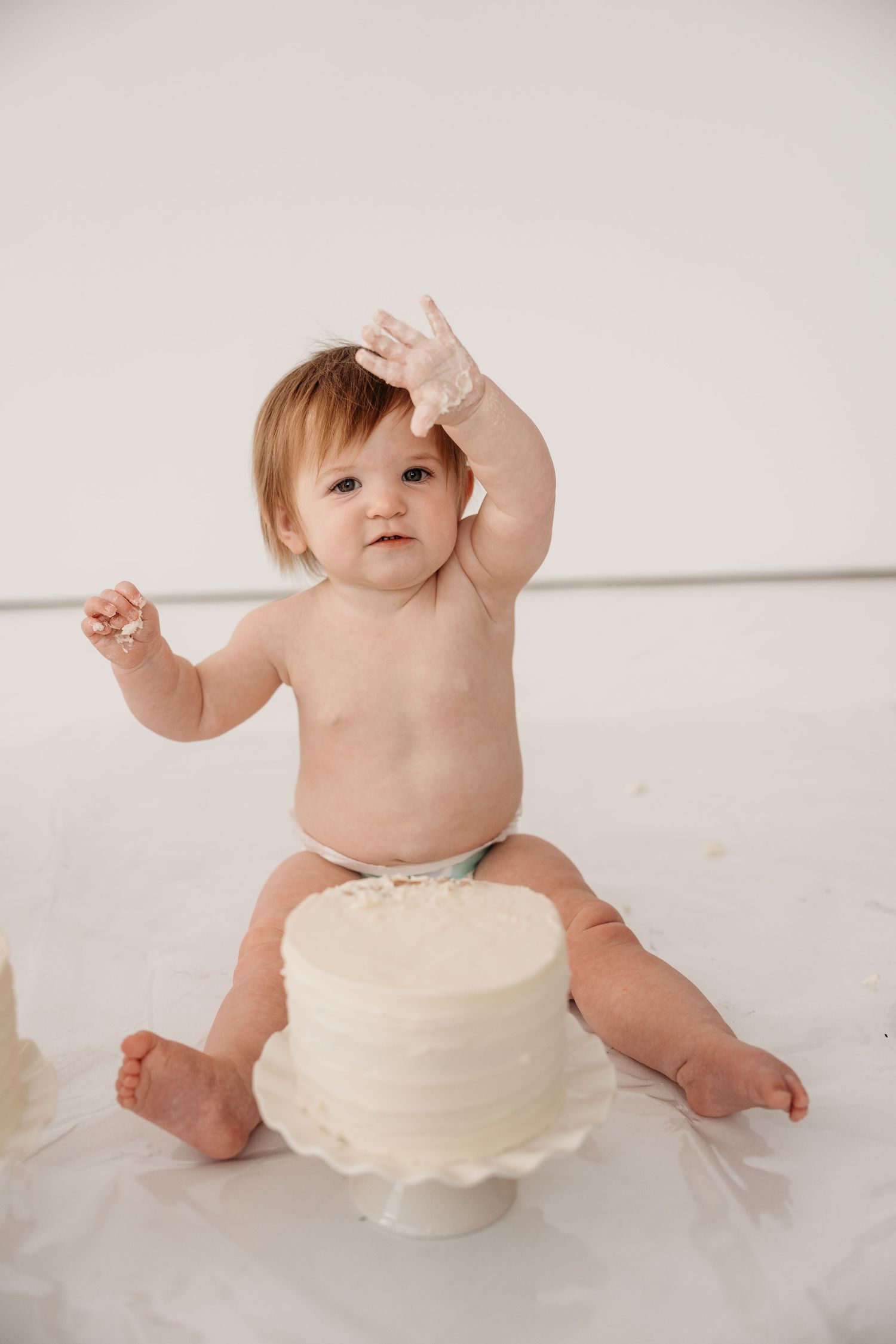 Four sequential photos show a baby wearing a white diaper sitting and playing on a white background.