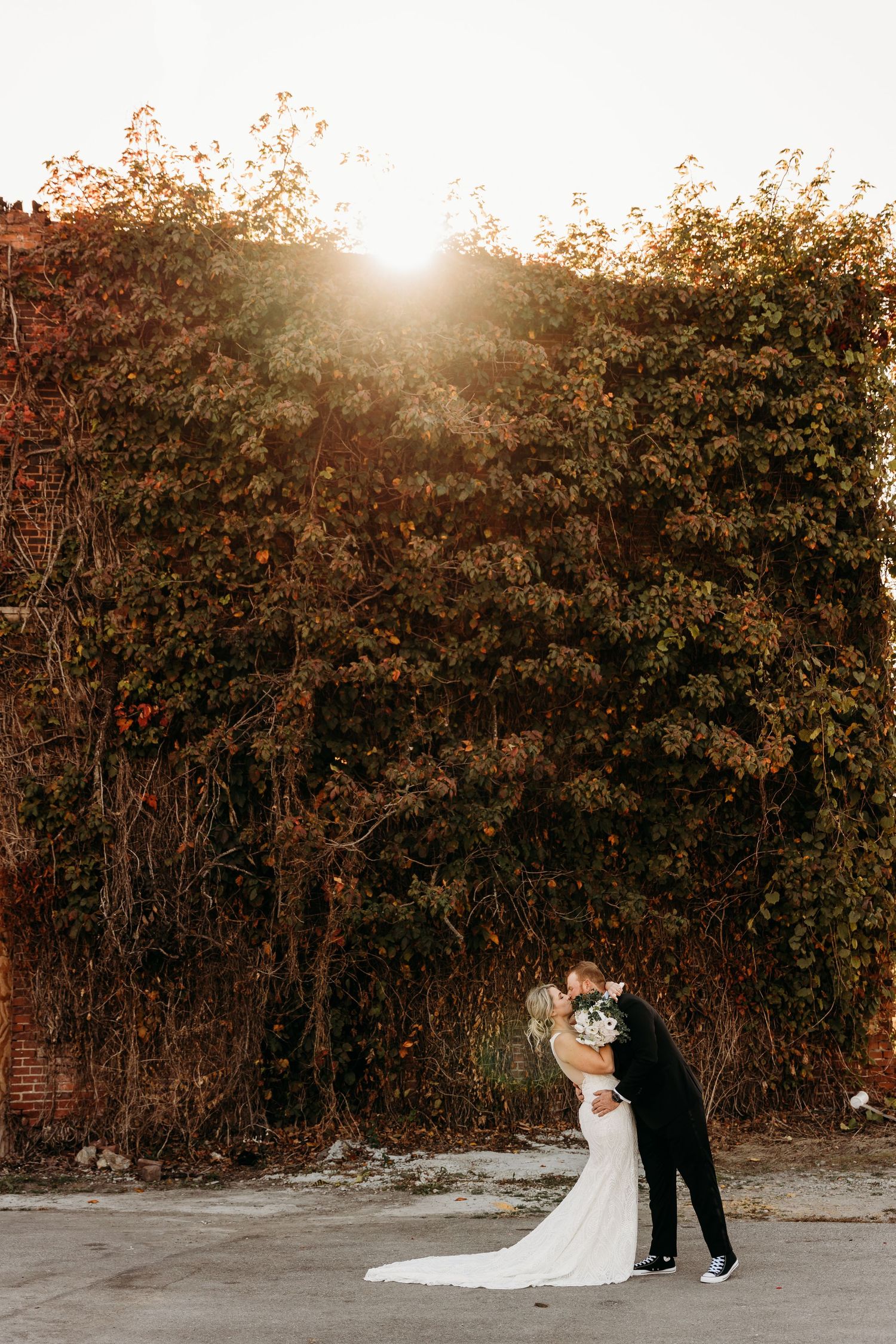 A romantic sunset silhouettes a couple embracing against autumn foliage and golden light.