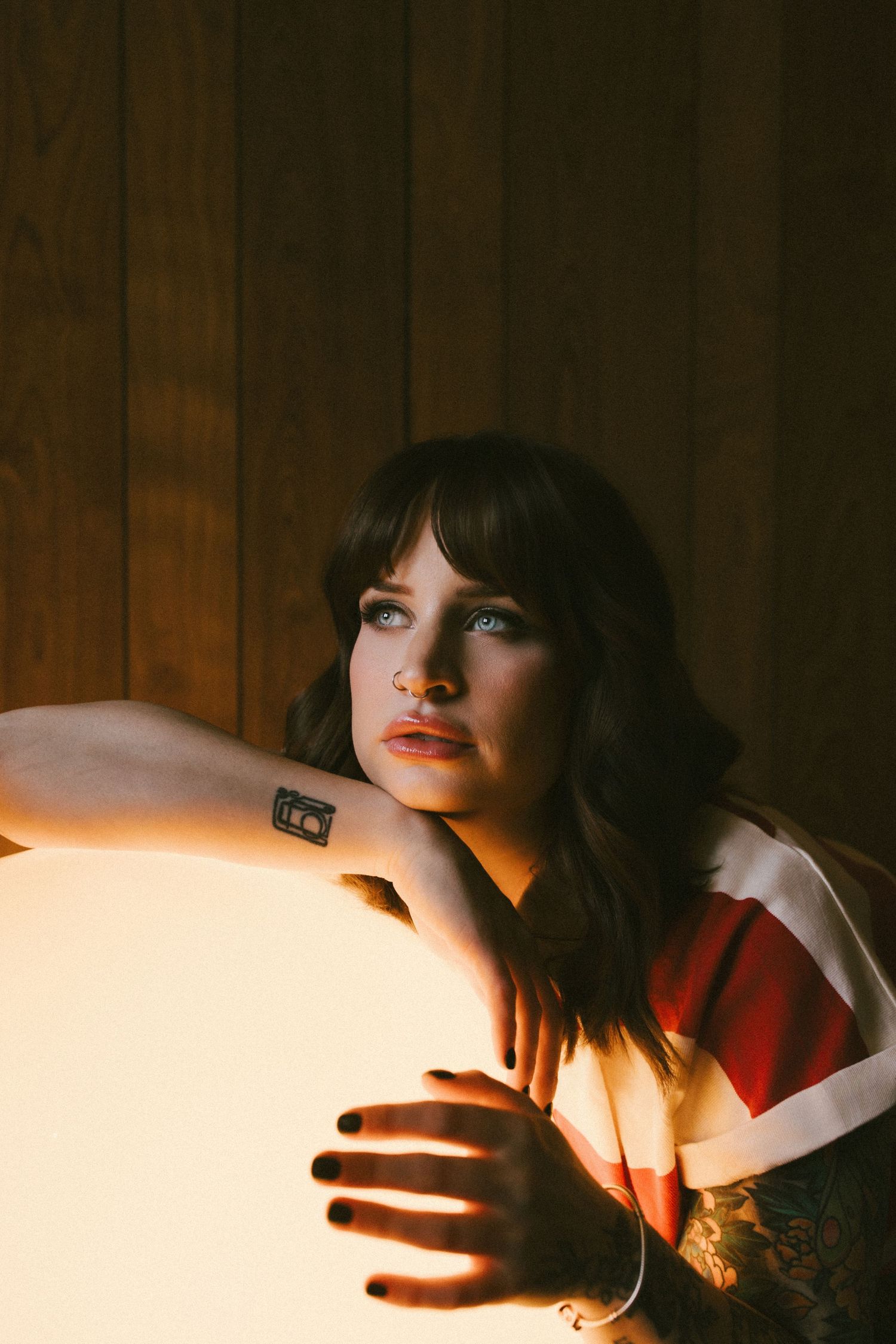 A moody portrait series in warm lighting shows a figure in red against dark wood paneling creating dramatic shadows.