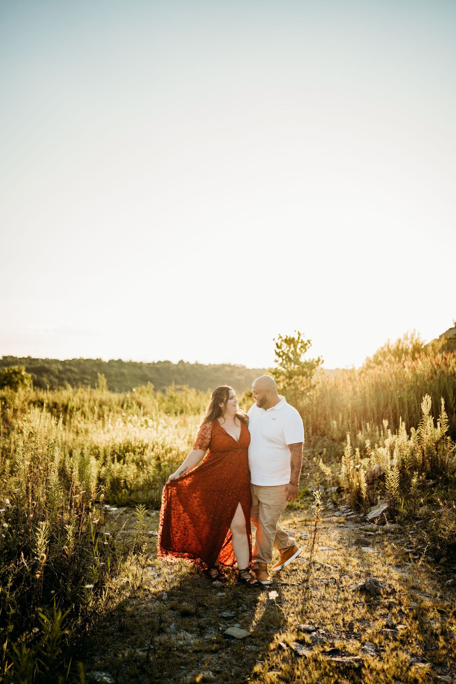 A couple walks through a golden field of wildflowers at sunset, creating a romantic silhouette against the warm sky.
