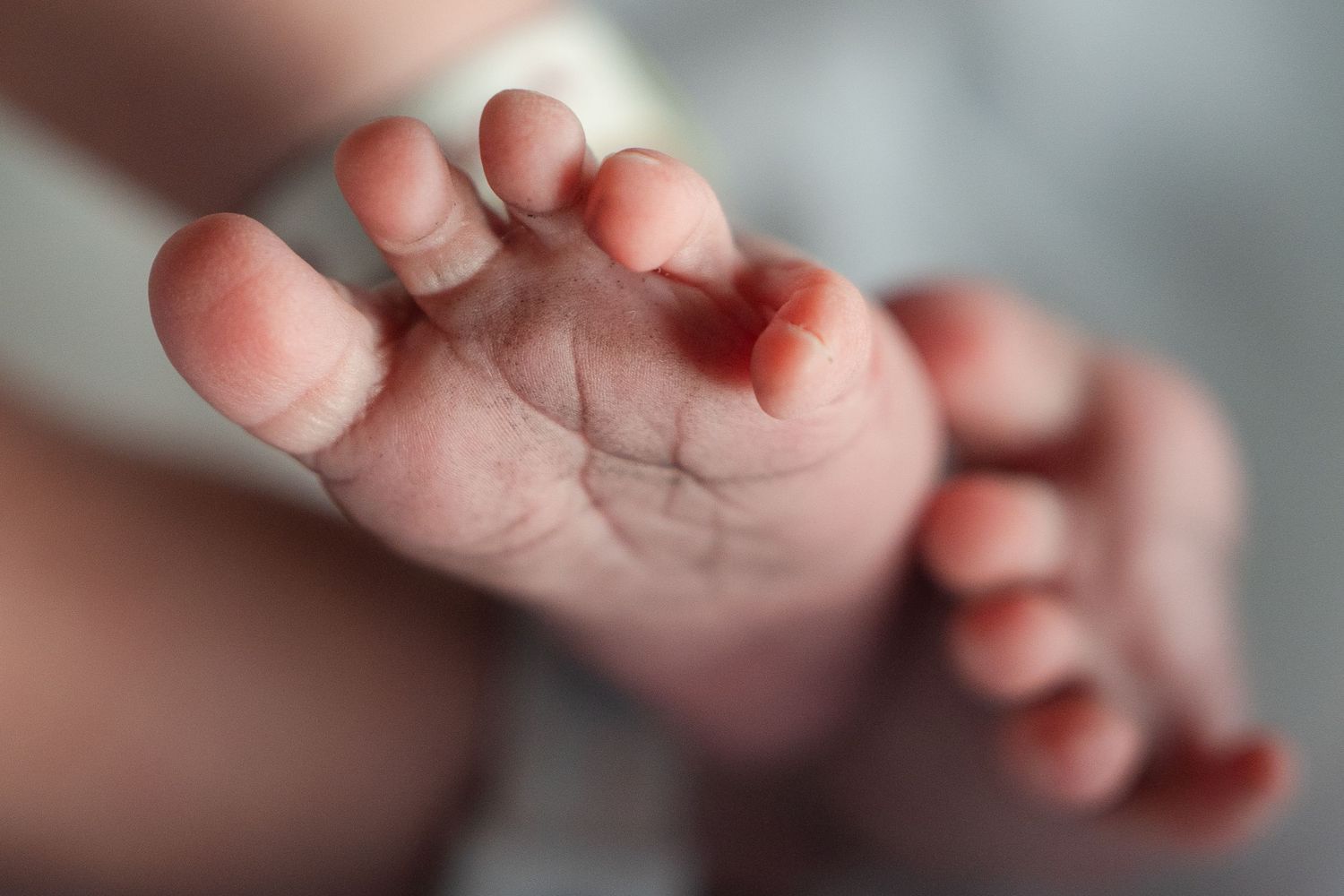 Close-up macro shot of a newborn baby's tiny foot showing delicate skin and natural lines.