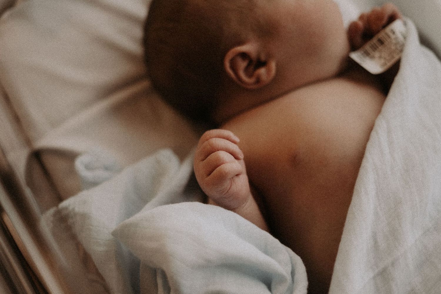 Close-up of sleeping infant wrapped in soft white blanket.