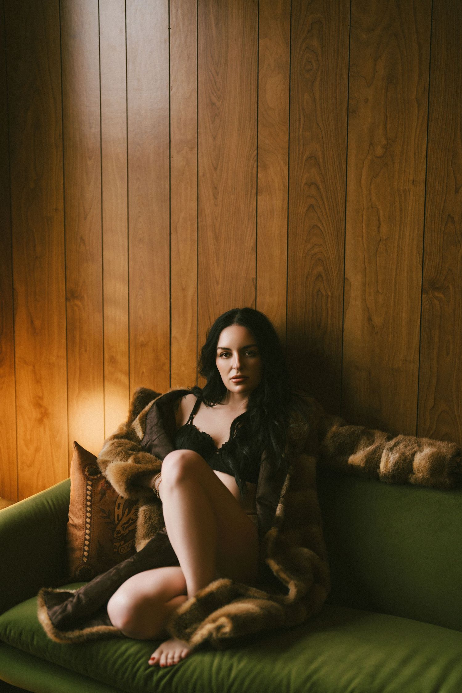 A figure rests on a green couch against wood paneling in a moody, atmospheric series of photos.