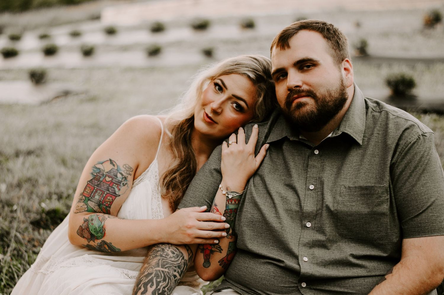 A couple in casual attire sits together on rocky terrain during a romantic outdoor photo session.