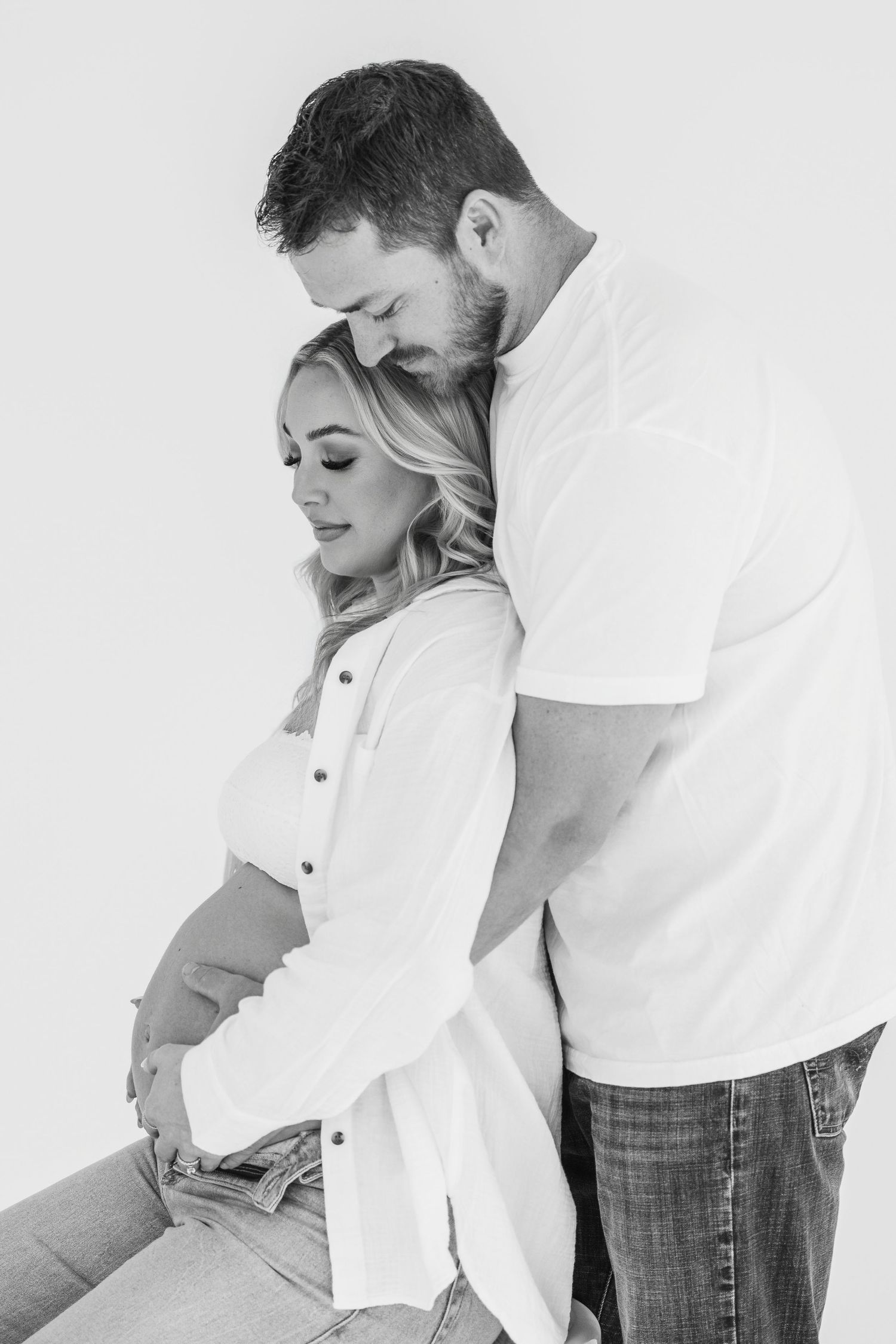 Black and white photo series showing a tender romantic embrace between two people in casual white and denim clothing.