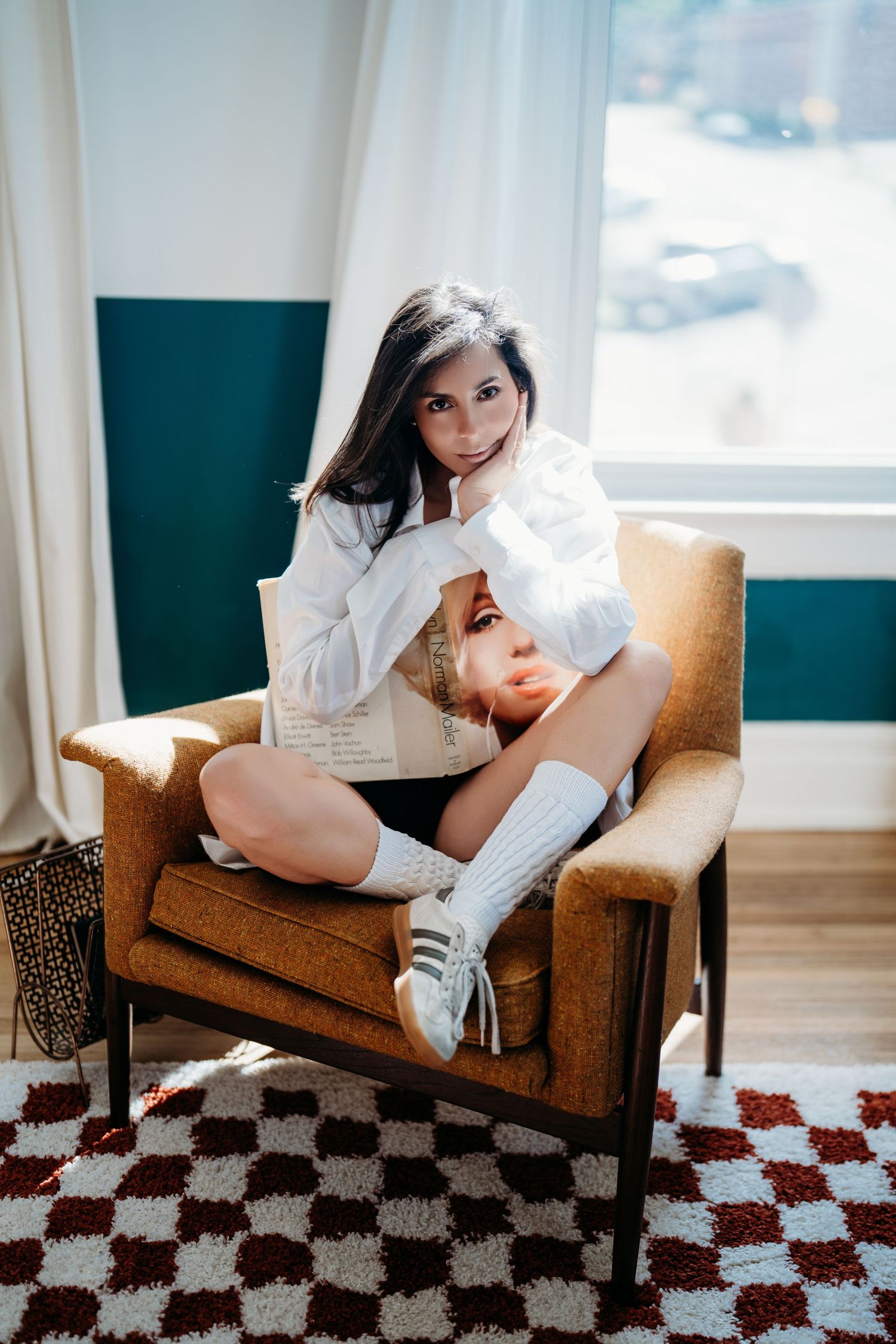 Three connected photos show someone in white clothing lounging on a brown armchair against a checkered floor pattern.