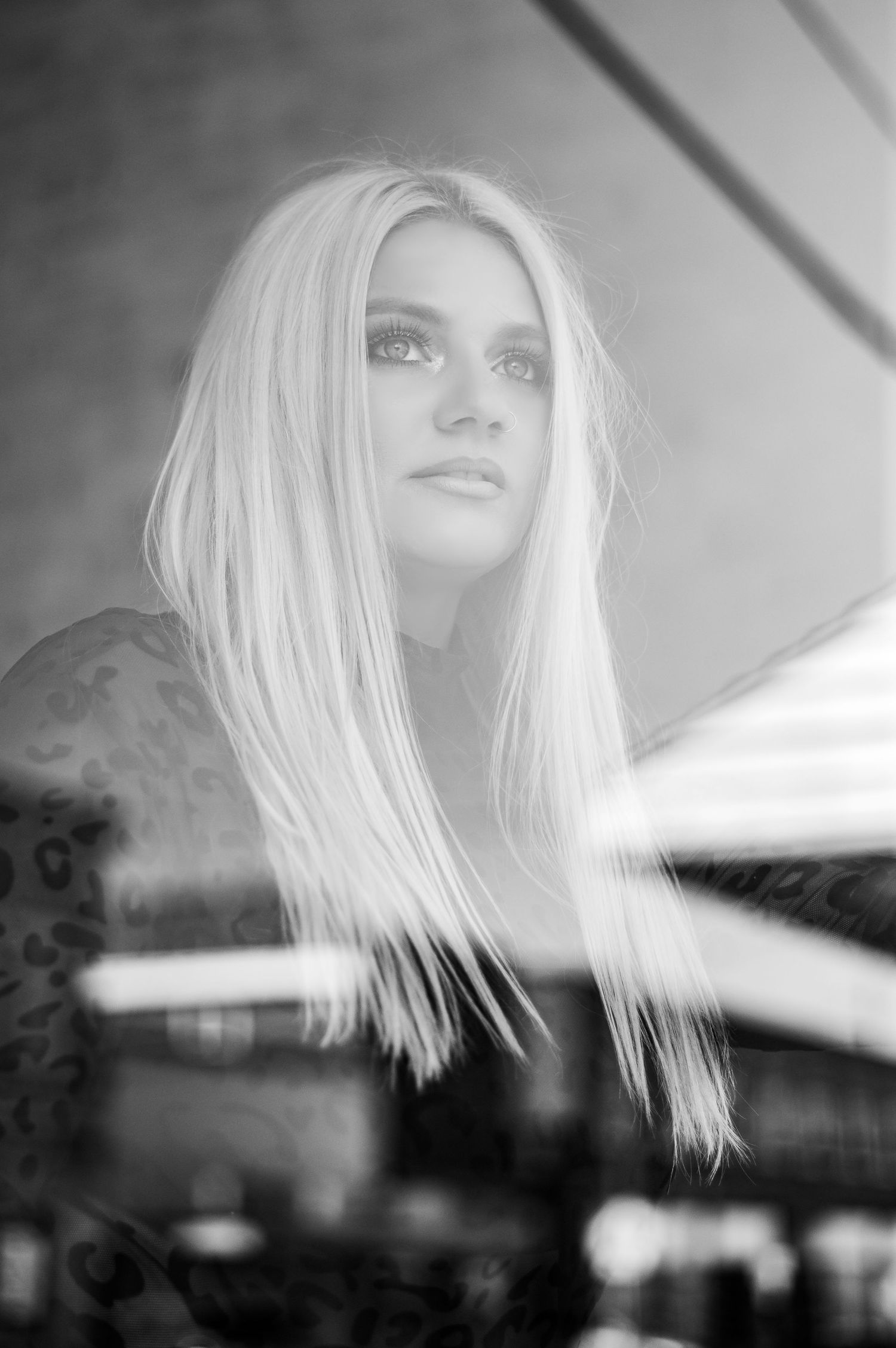 Black and white portrait through window glass with dramatic lighting.