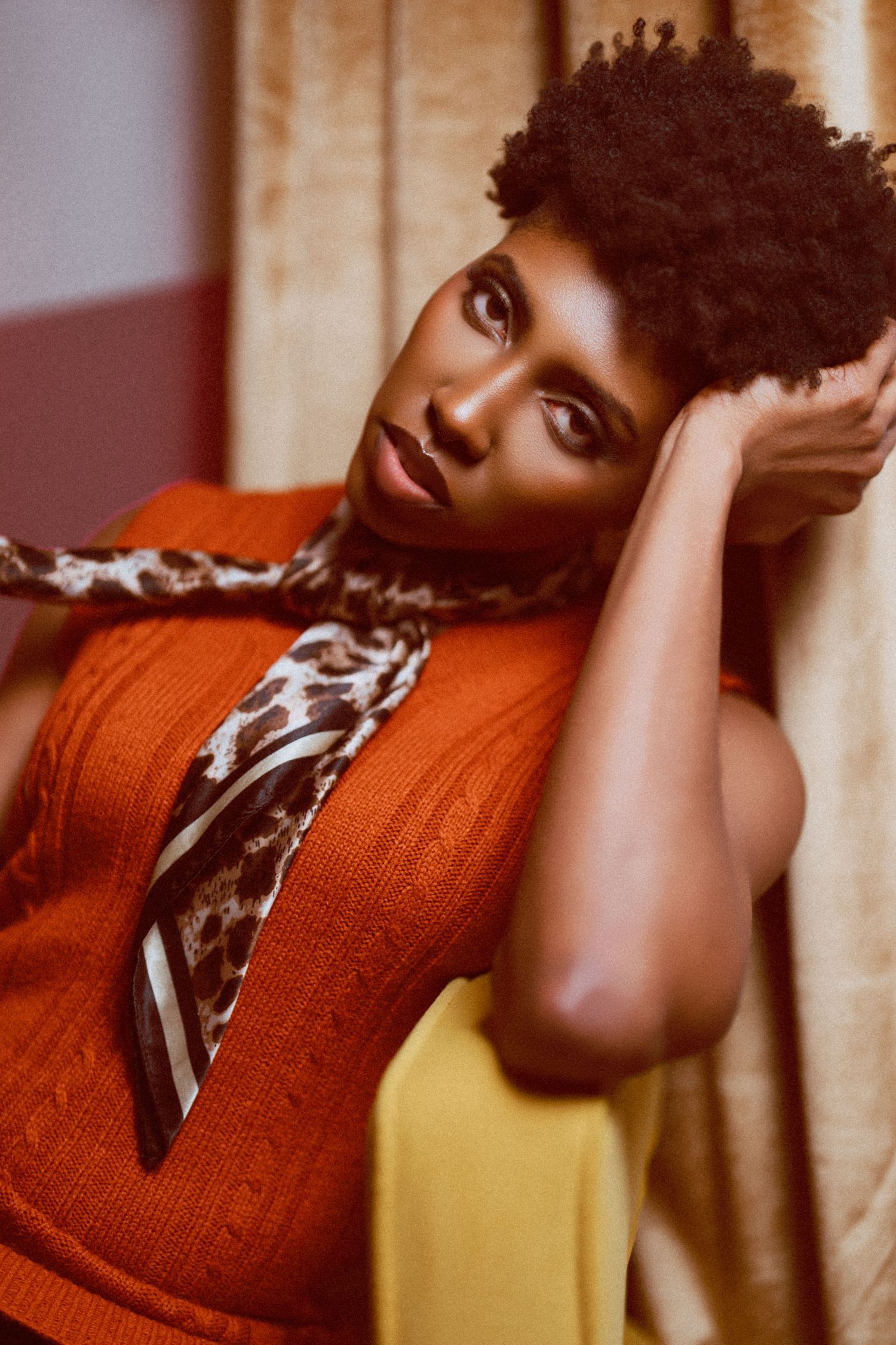 A series of artistic portraits showing someone in a rust-colored sweater posing expressively against a warm-toned background.
