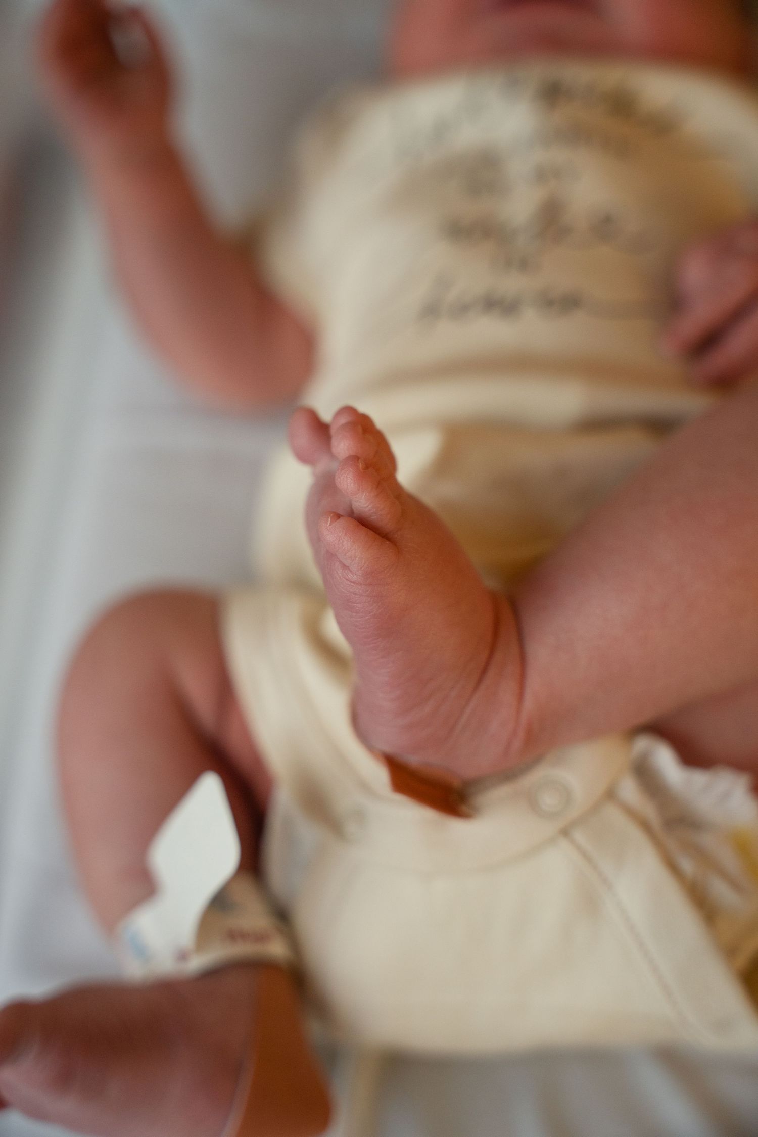 Close-up details of tiny newborn baby fingers grasping and touching soft fabric.