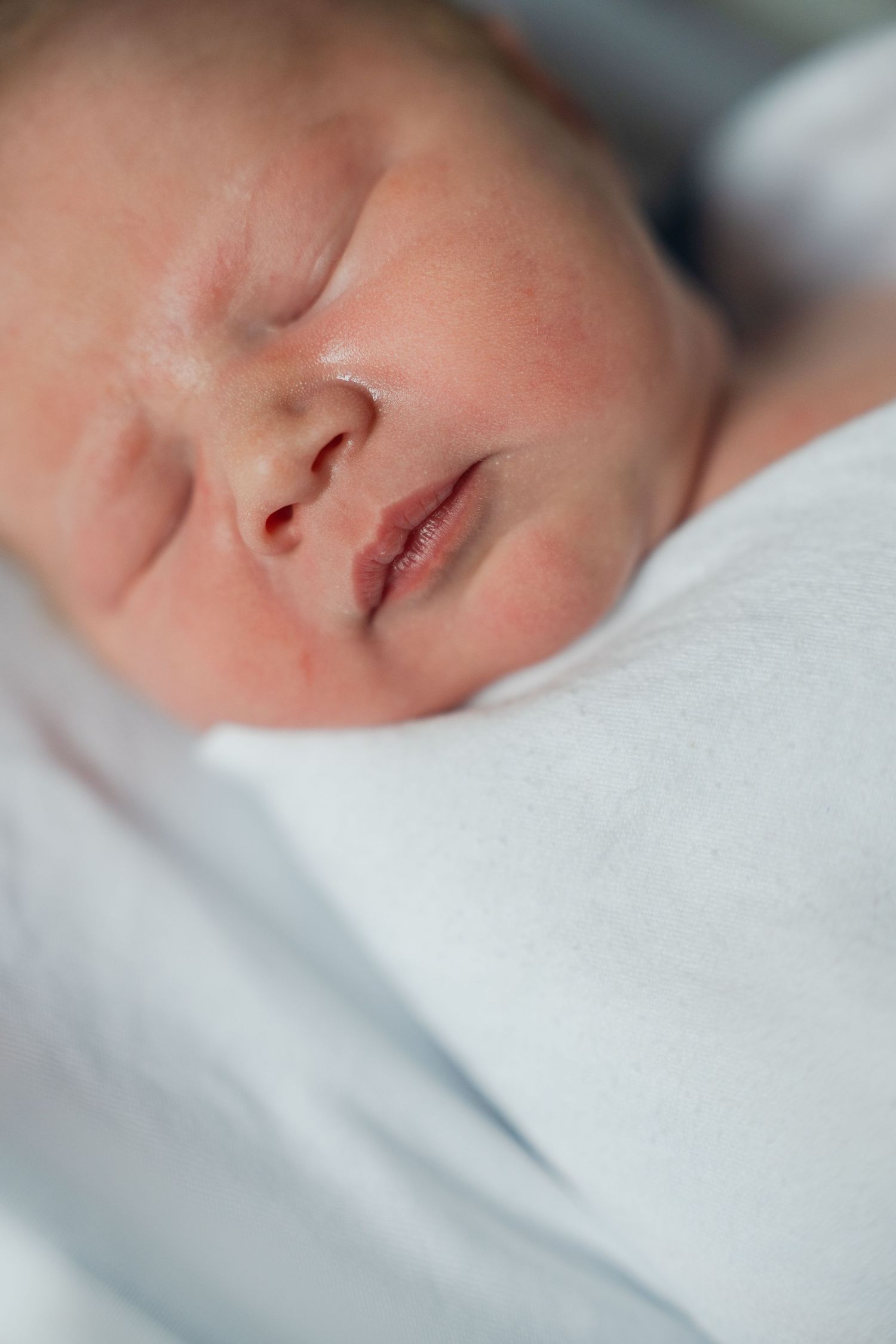 A series of close-up photos showing a sleeping baby's face from different angles wrapped in soft white blankets.