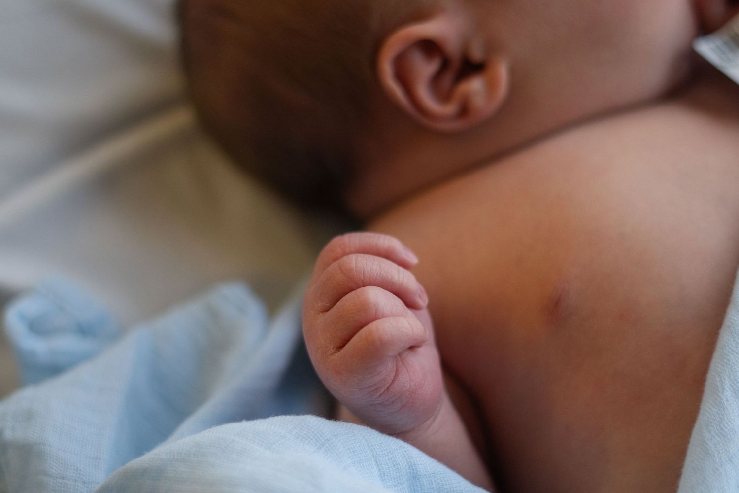 A close-up view of a newborn baby sleeping peacefully in white bedding.