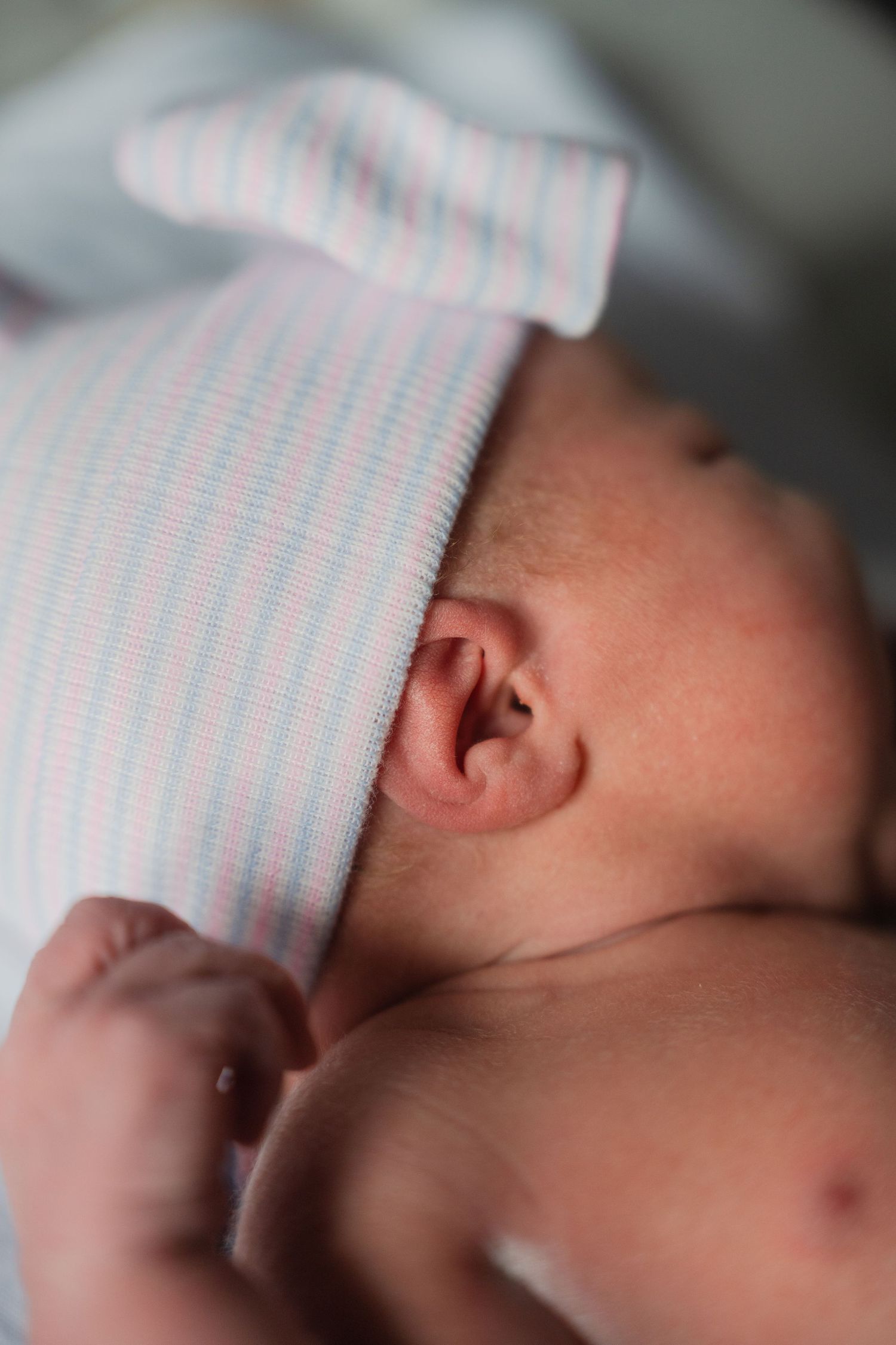 Close-up view of a sleeping newborn baby's face partially covered with a striped blanket.