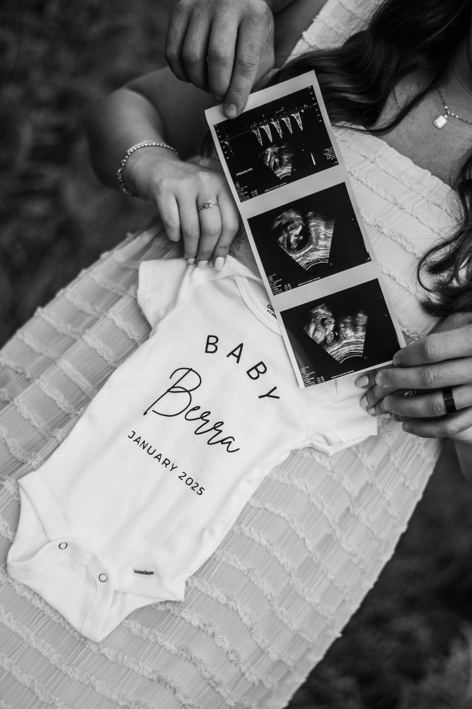 Black and white photo series showing hands writing baby announcement text next to ultrasound photos on textured paper.