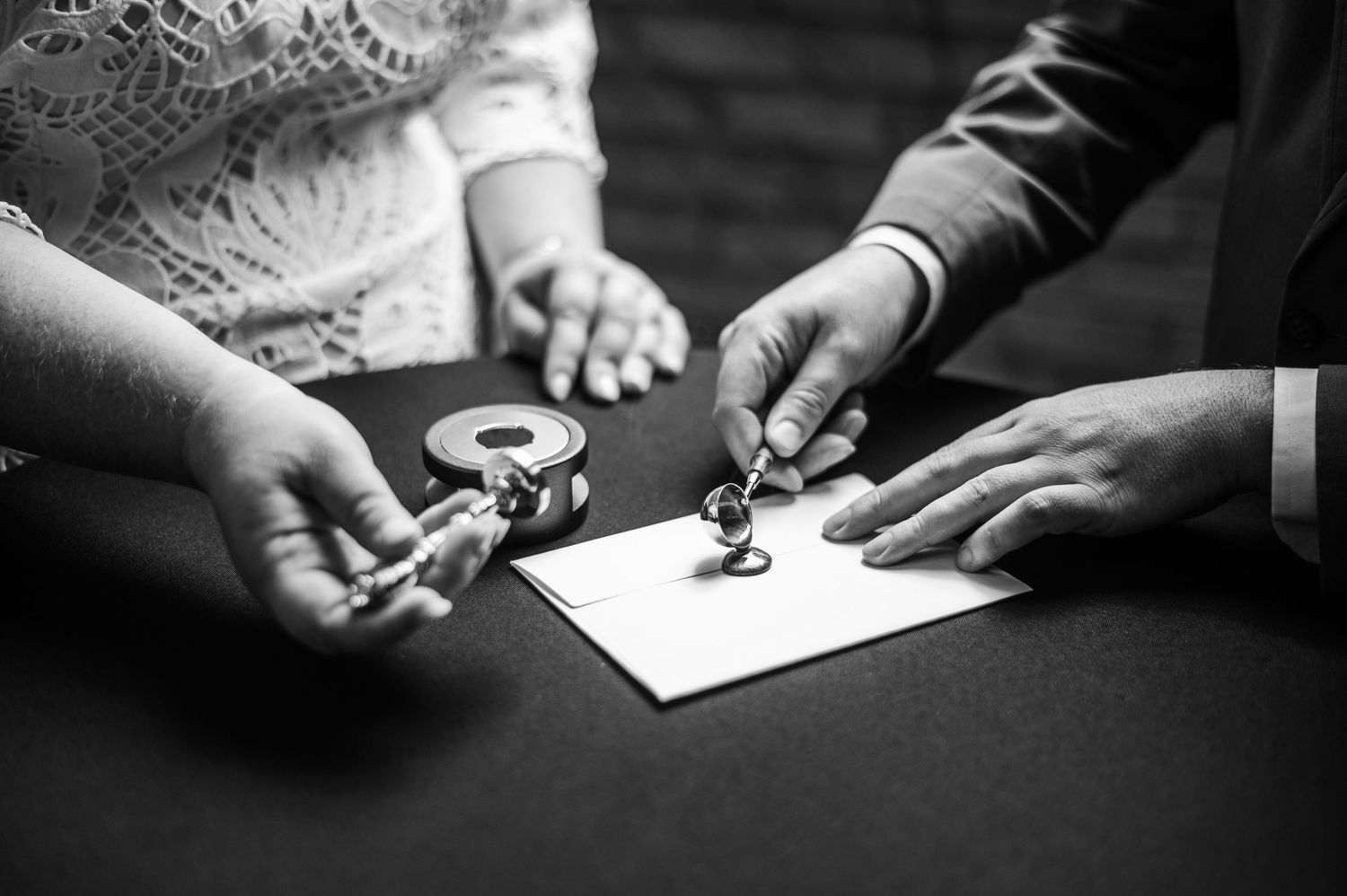 Black and white close-up images showing hands signing or writing documents with pens in sequence.