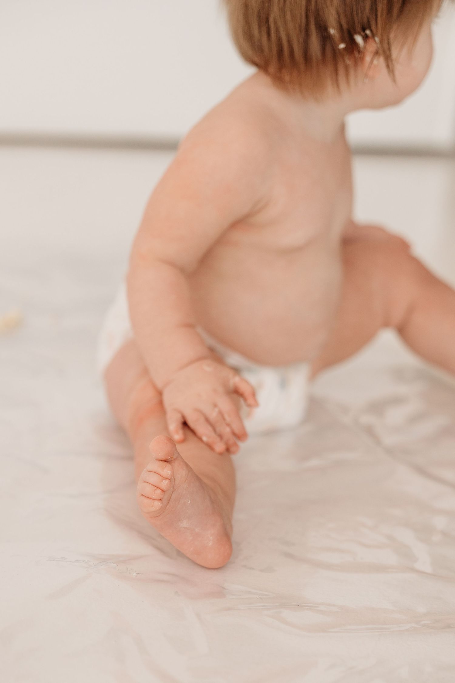 Close-up view of tiny baby feet walking on a white textured surface.