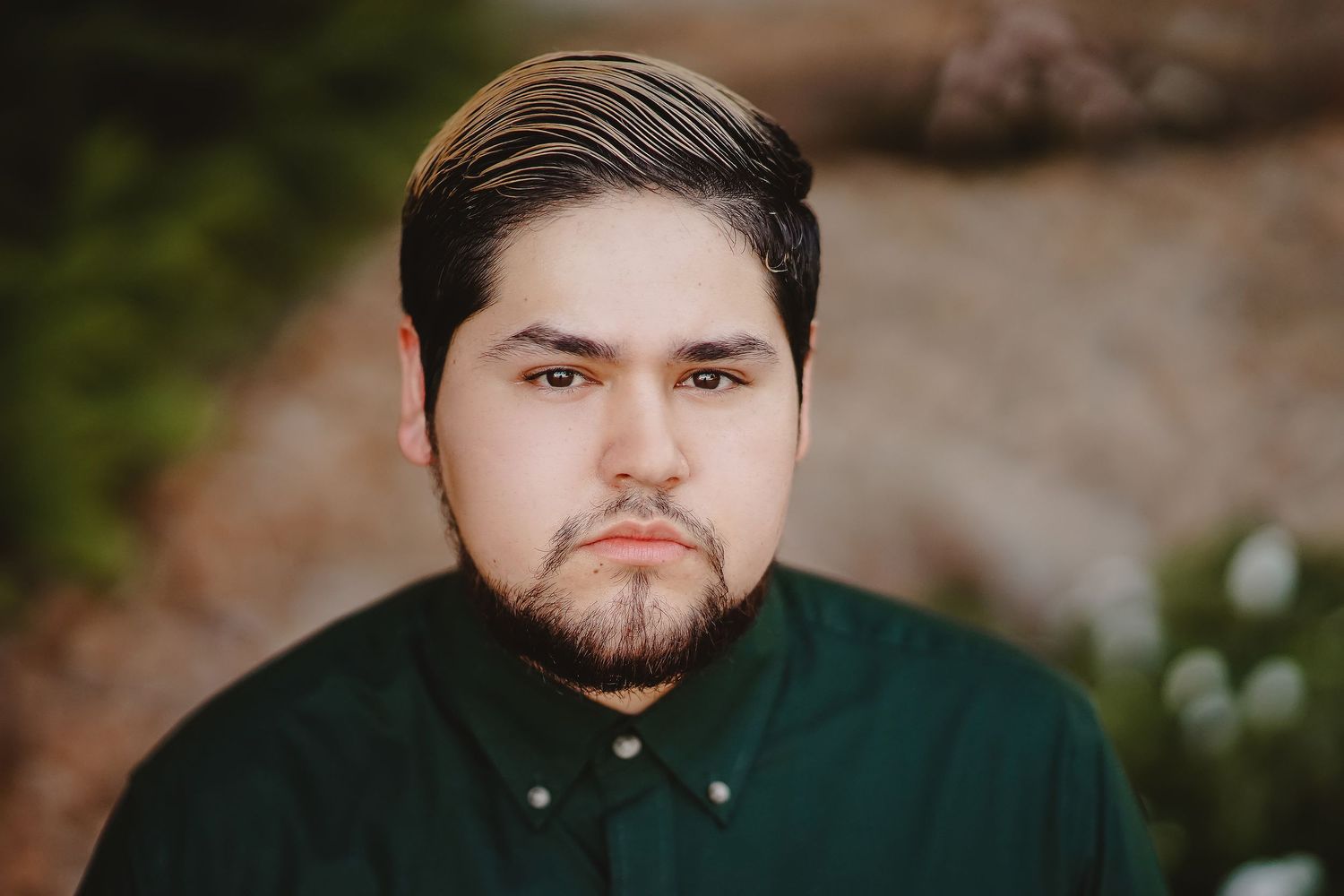 Professional portrait of person in dark green button-up shirt with styled dark hair.