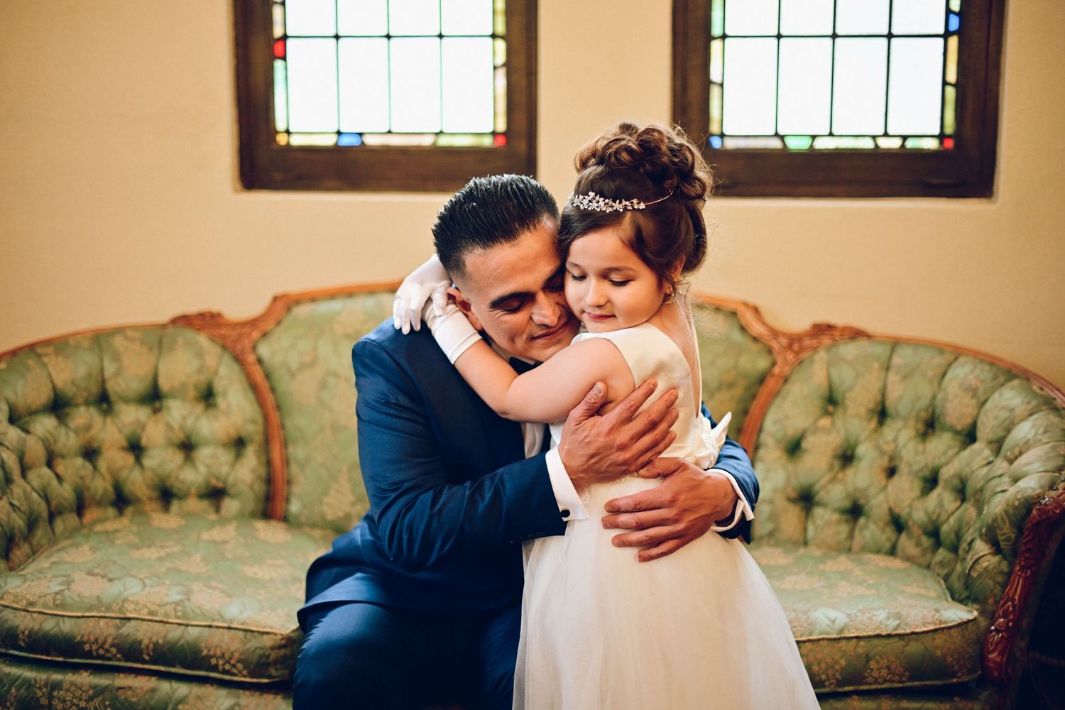 An intimate moment shared on an antique tufted sofa in a wedding venue.