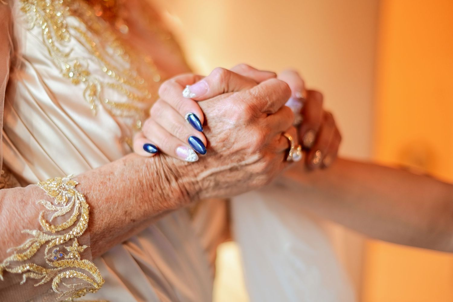 Close up of hands with rings and jewelry against cream-colored fabric.