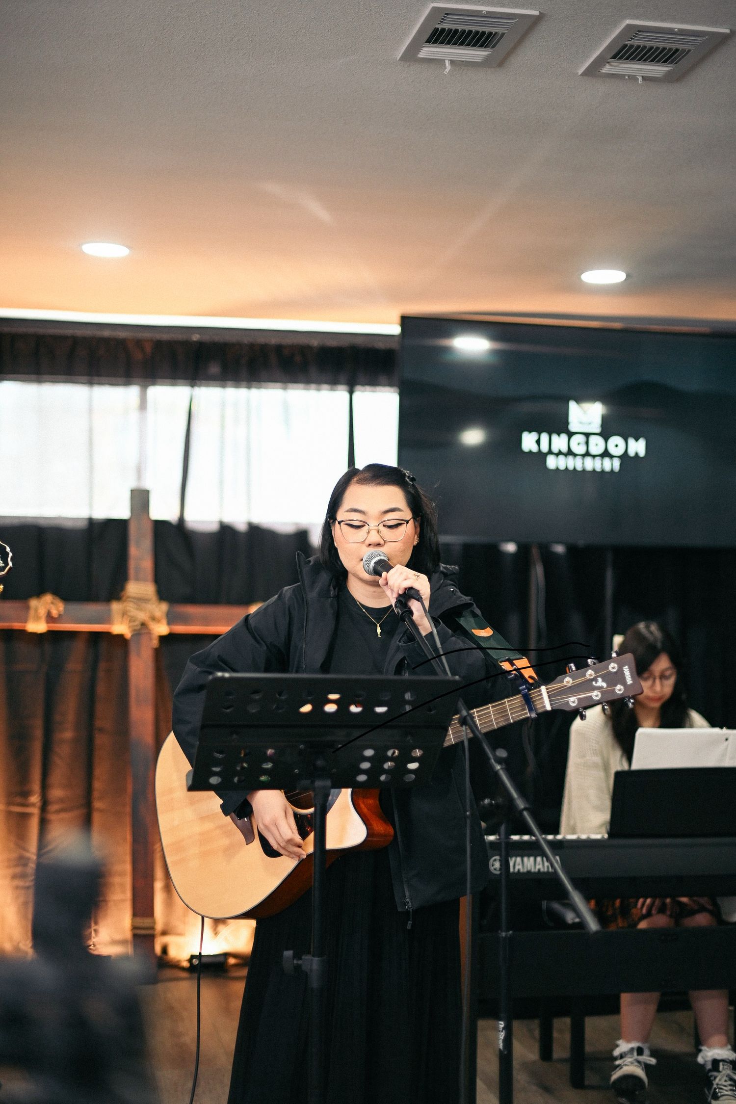 Musician performing with acoustic guitar at church service with warm lighting.