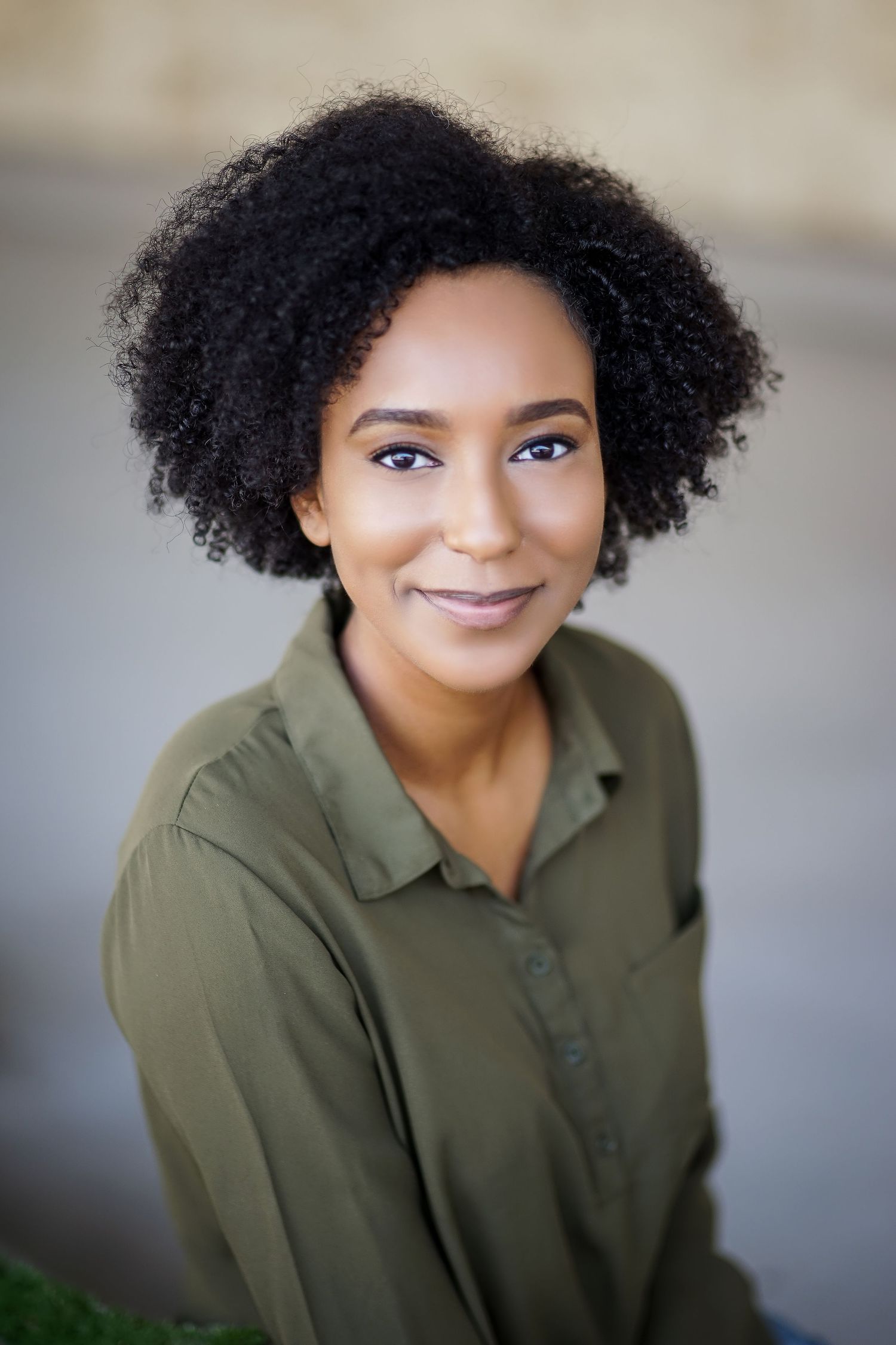 Professional headshot of person in olive green polo shirt with natural curly hair.