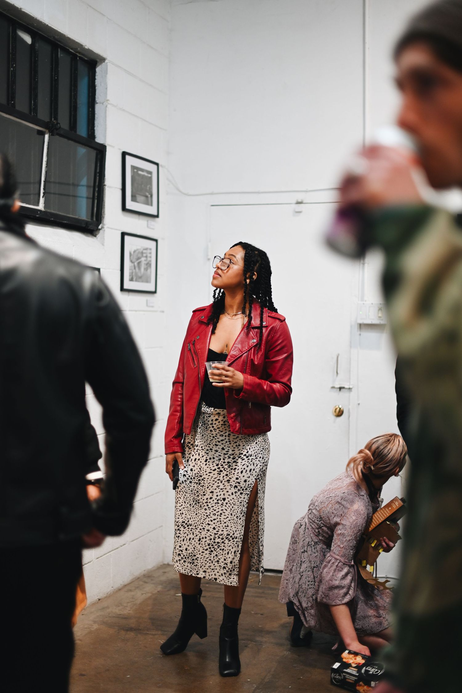 Woman in red jacket and leopard print skirt laughing during a casual indoor gathering.