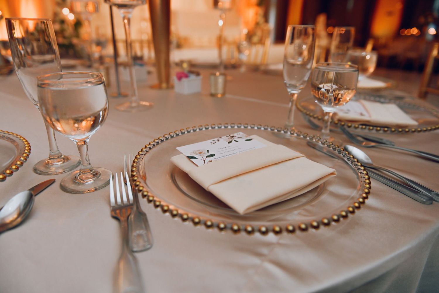 Elegant place setting with beaded charger plate and glassware at a formal dinner.