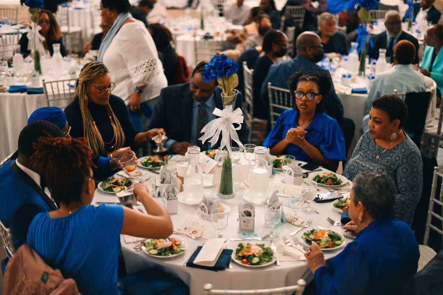 Round table dinner setting with guests enjoying a meal at an elegant event.