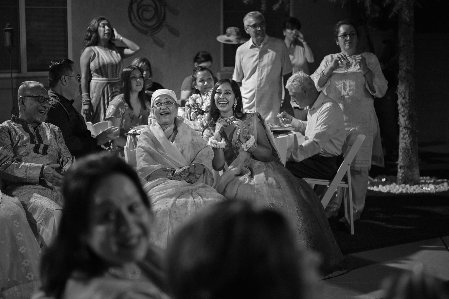 Black and white candid shot of wedding guests enjoying reception entertainment.
