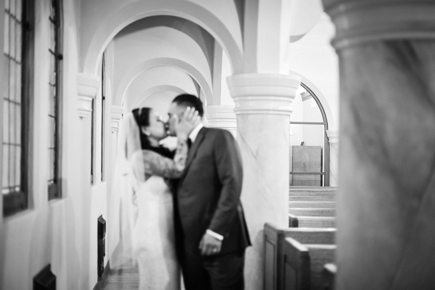 Black and white romantic moment under arched hallway interior.