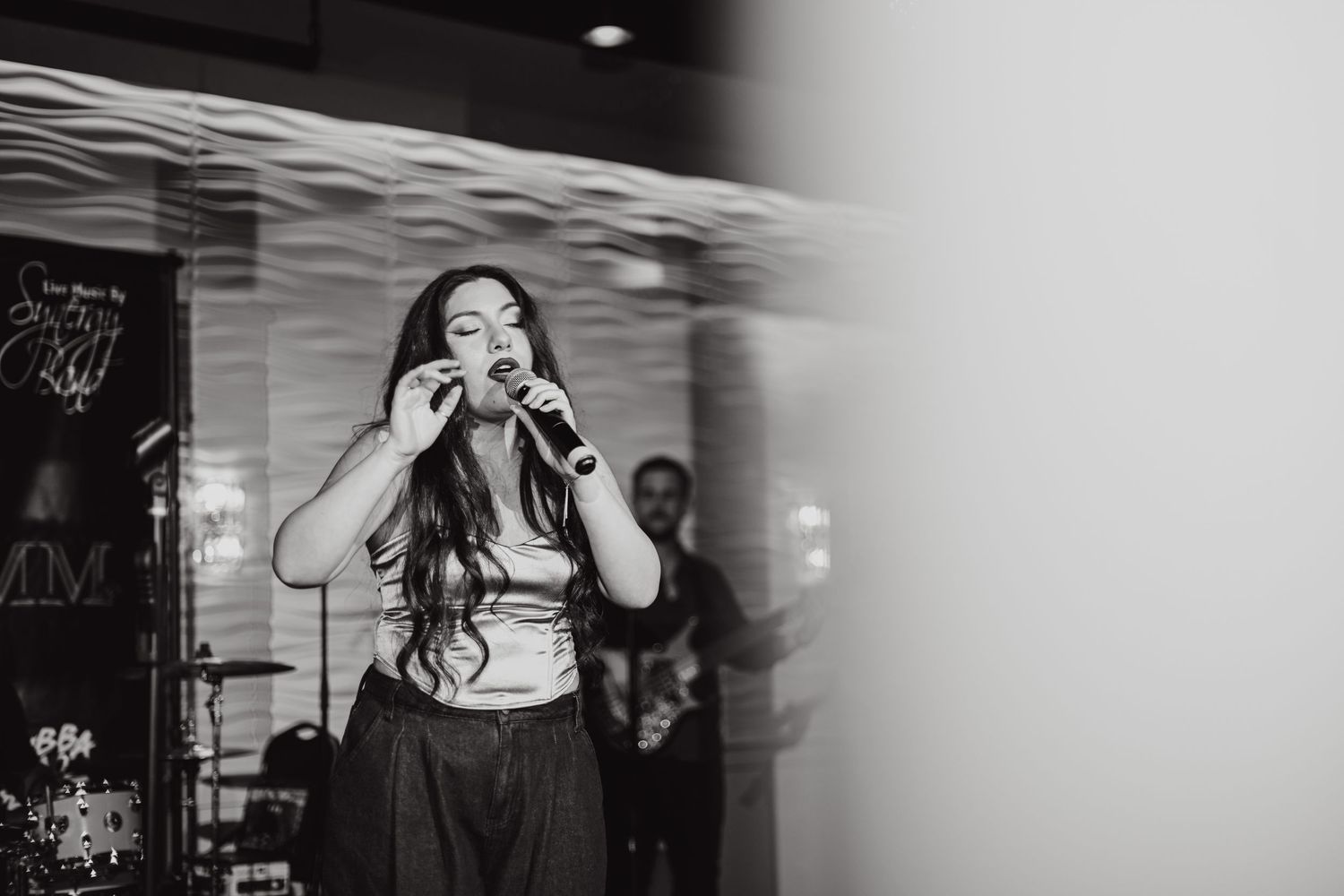 Monochrome shot of a performer singing passionately into a microphone on stage.