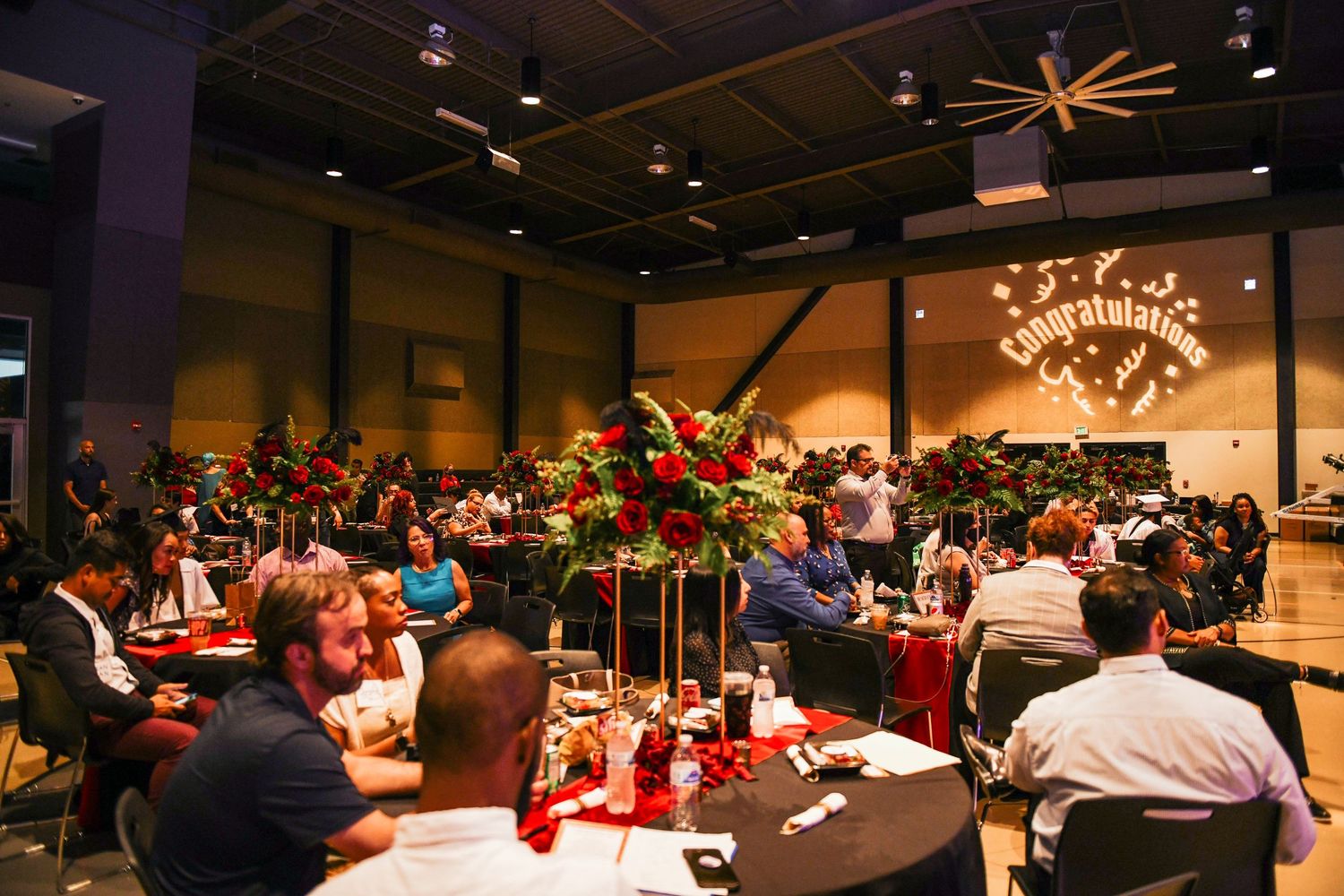 Large banquet hall filled with guests seated at round tables during an evening event.