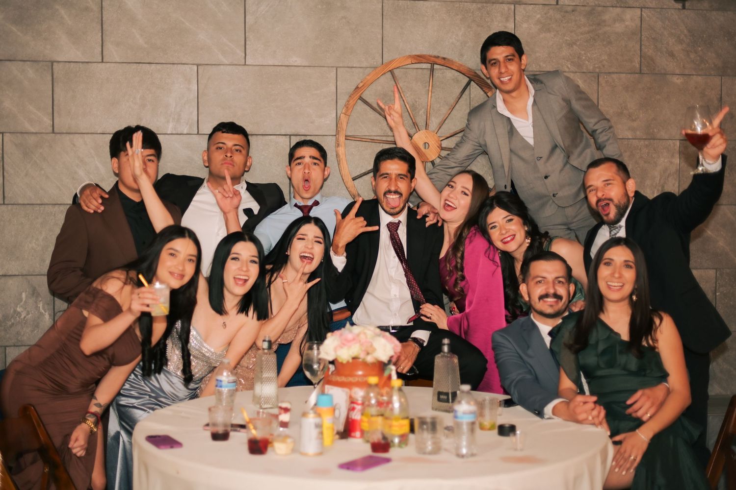 A festive group celebrating at a restaurant table with drinks and food.