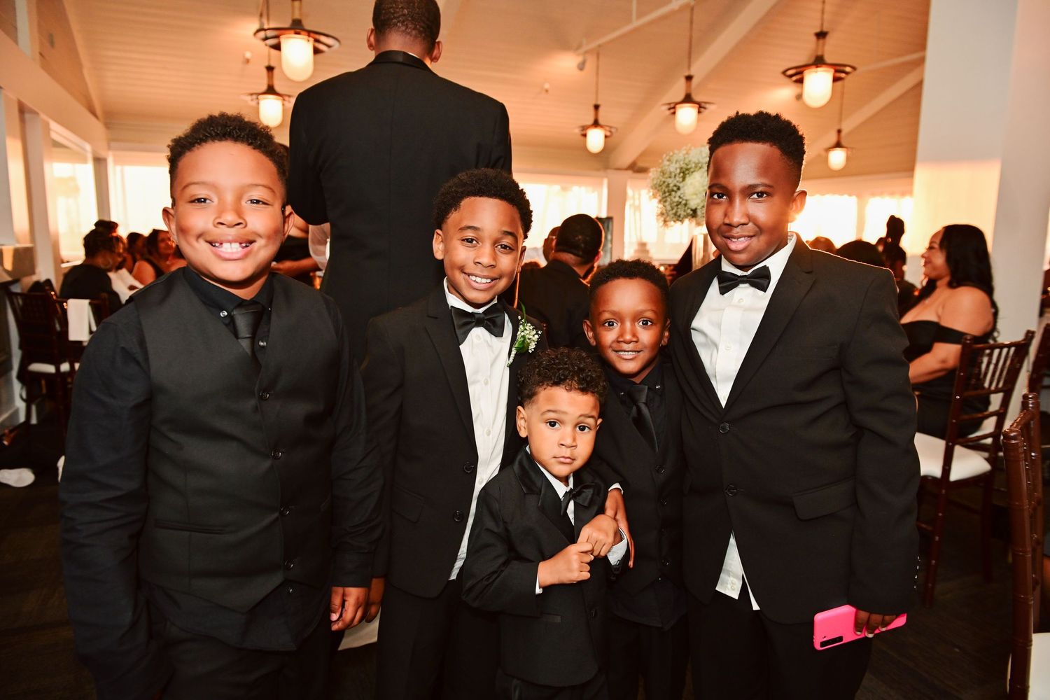 Young wedding guests in formal attire pose together at the reception.