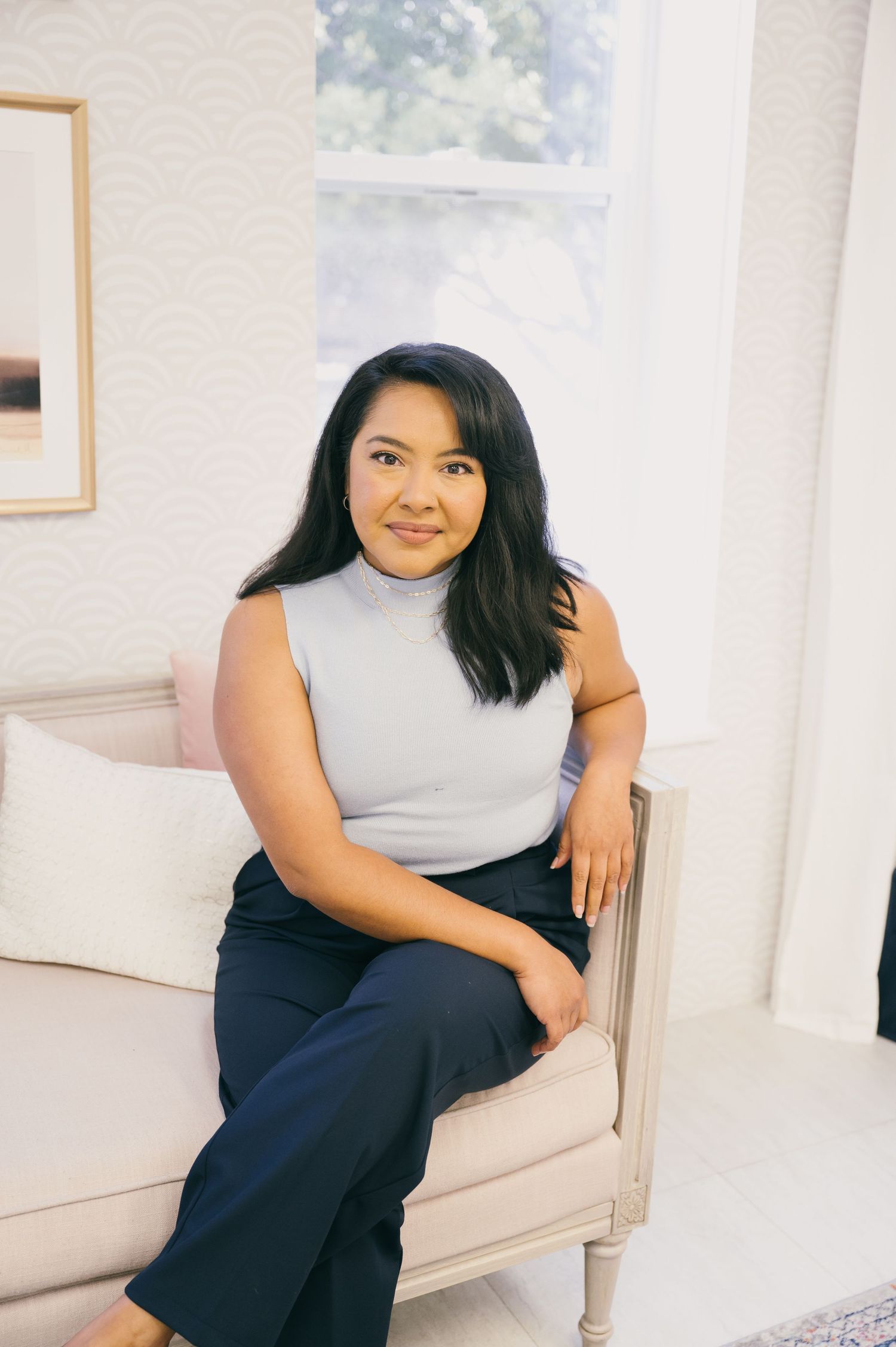 Person in sleeveless grey top sitting comfortably on beige couch.