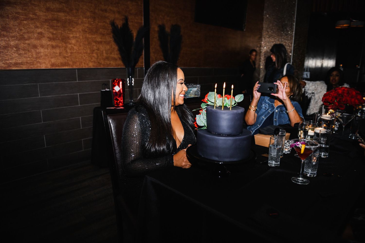 Guests celebrating at a dark lounge with bottle service and drinks.