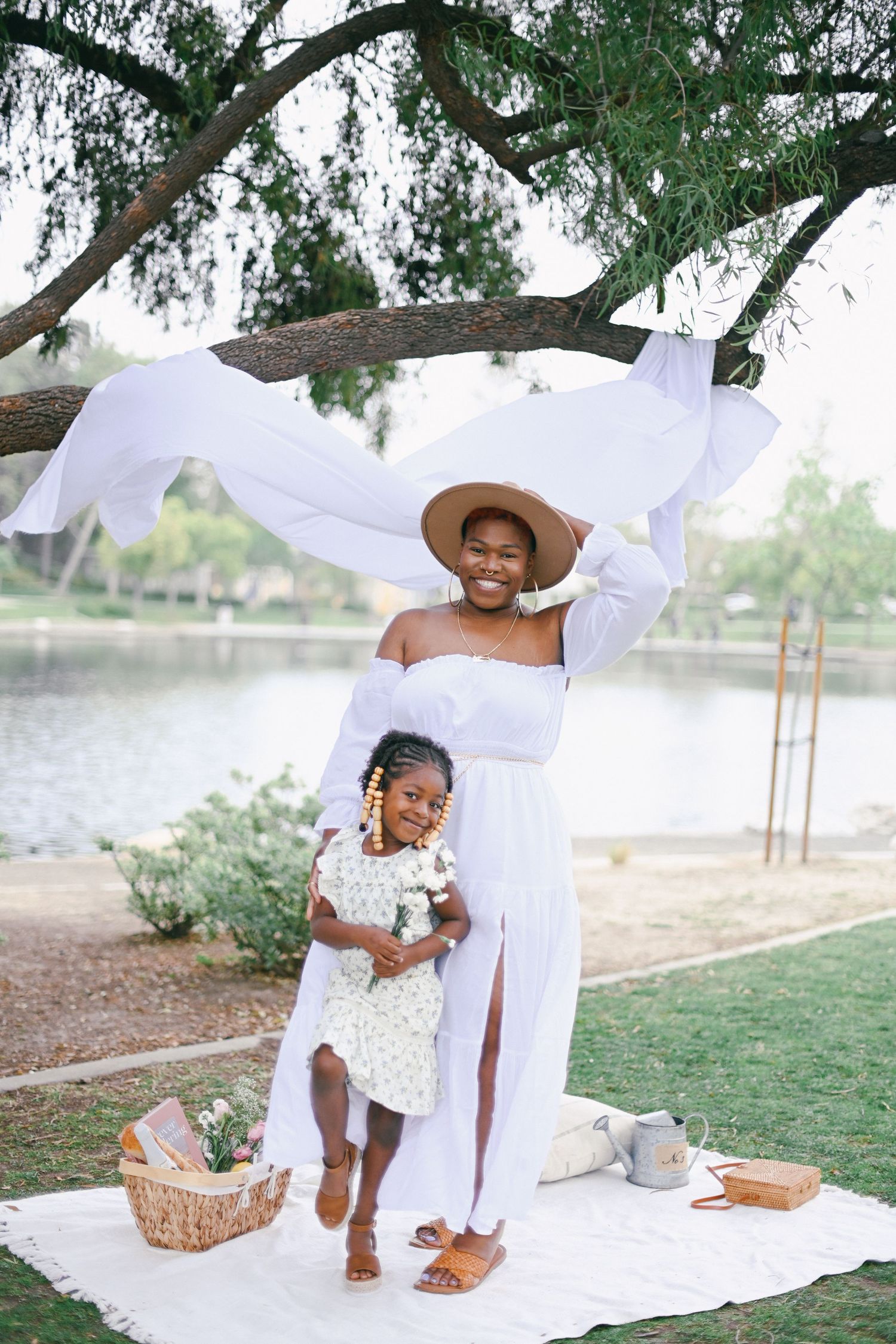 A joyful picnic scene by a lake with white linens and summer dresses.