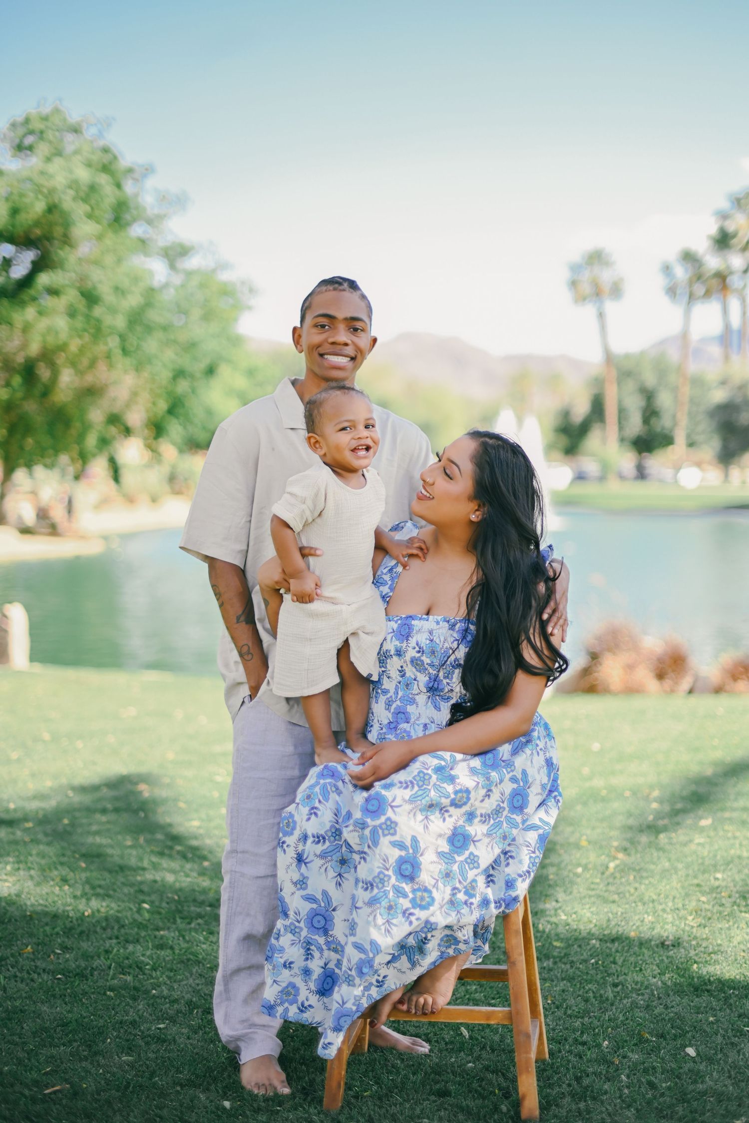 Family portrait by lake with palm trees in background.
