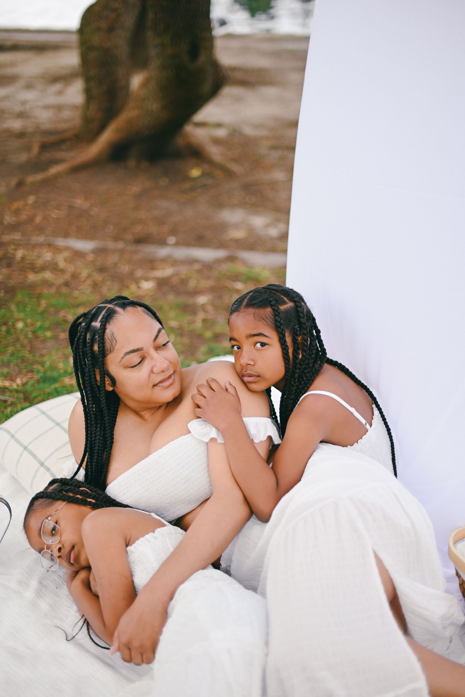 Intimate family portrait of mother and children resting together on white backdrop.