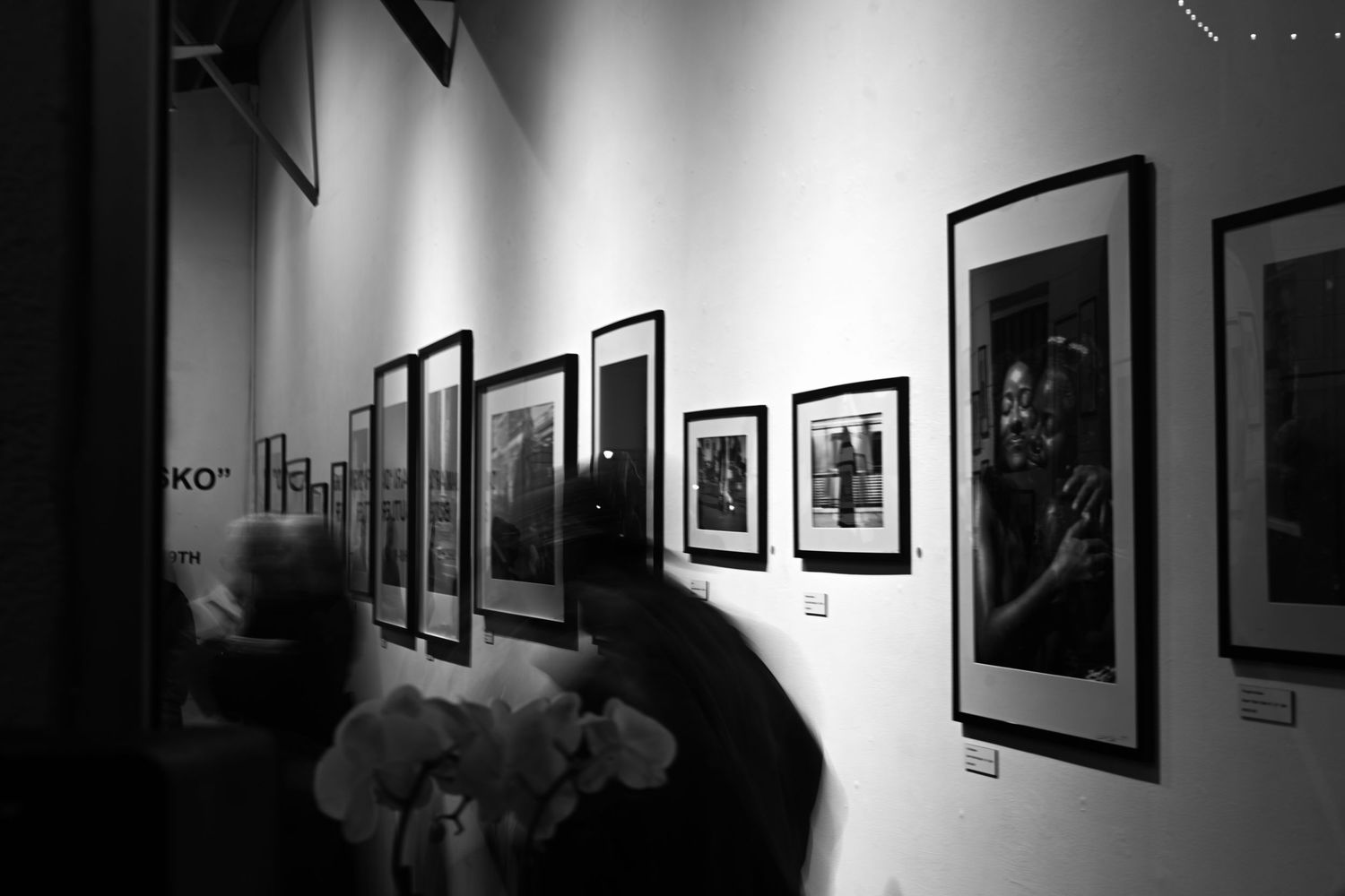 Black and white gallery wall displaying framed photographs in a dimly lit space.