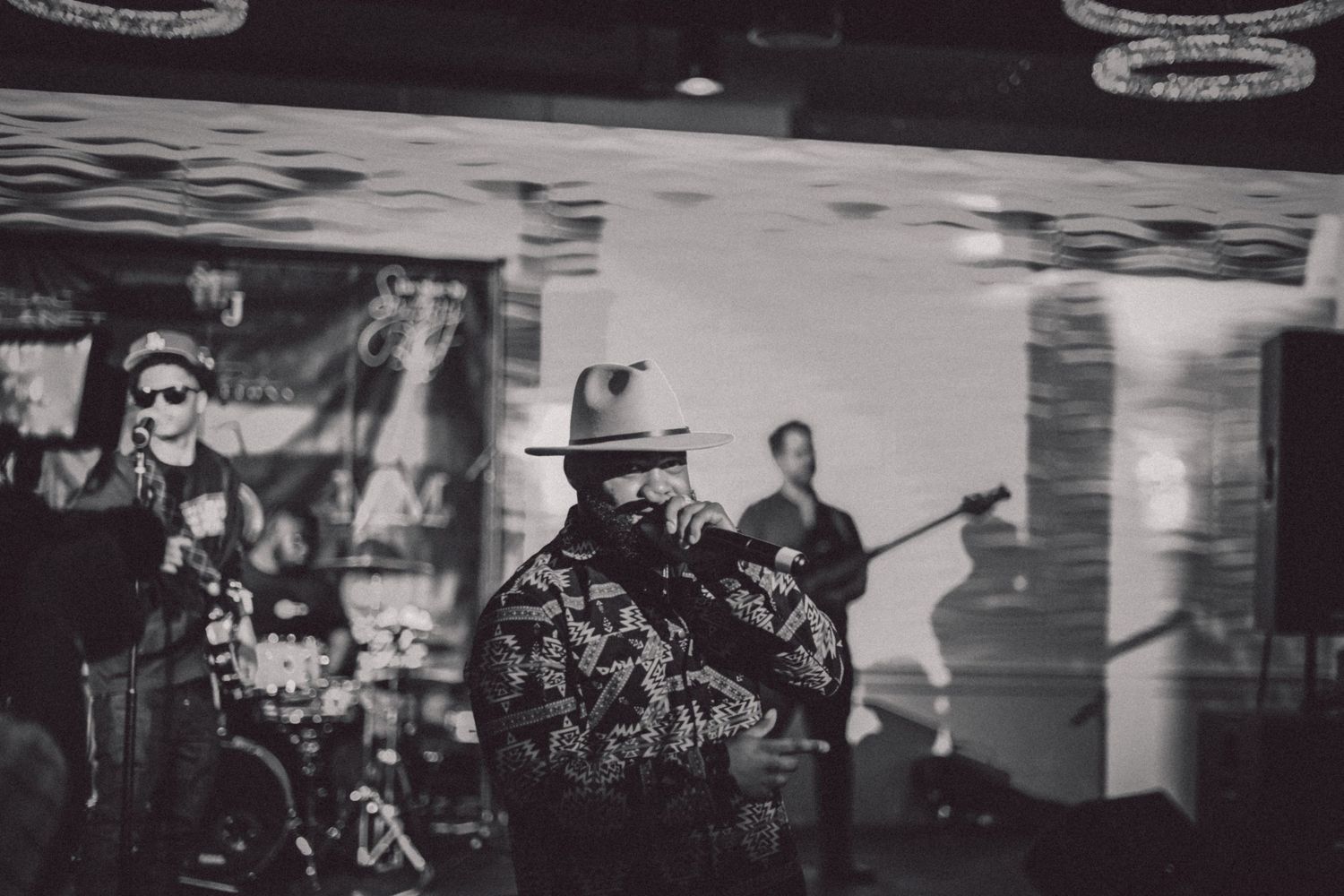 Black and white photo of musicians performing on stage with dramatic lighting.