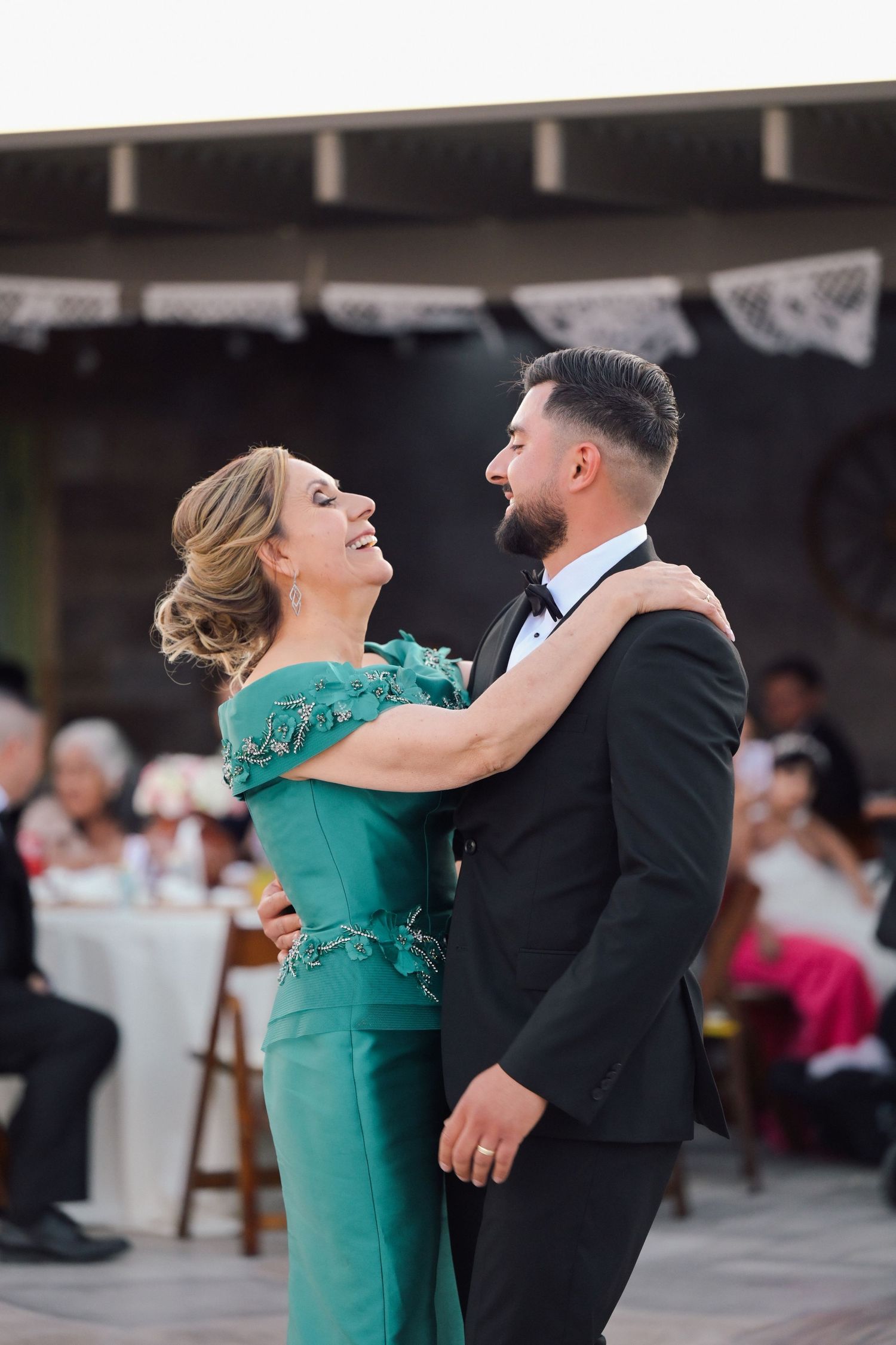 A couple dancing together at a wedding reception, with the woman wearing an elegant emerald green dress.