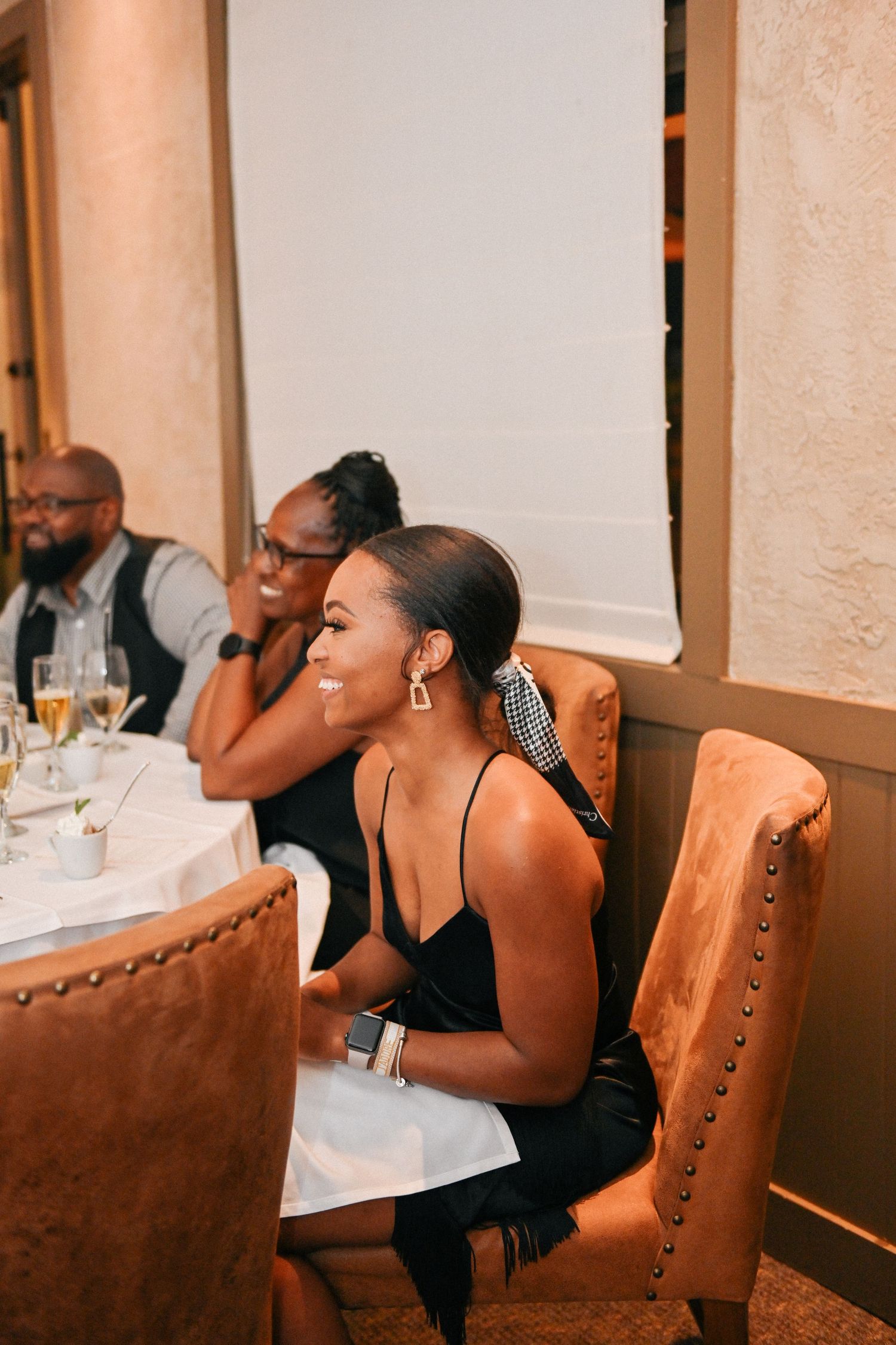 Guests enjoying themselves at an elegant dinner event with plush leather chairs and table settings.