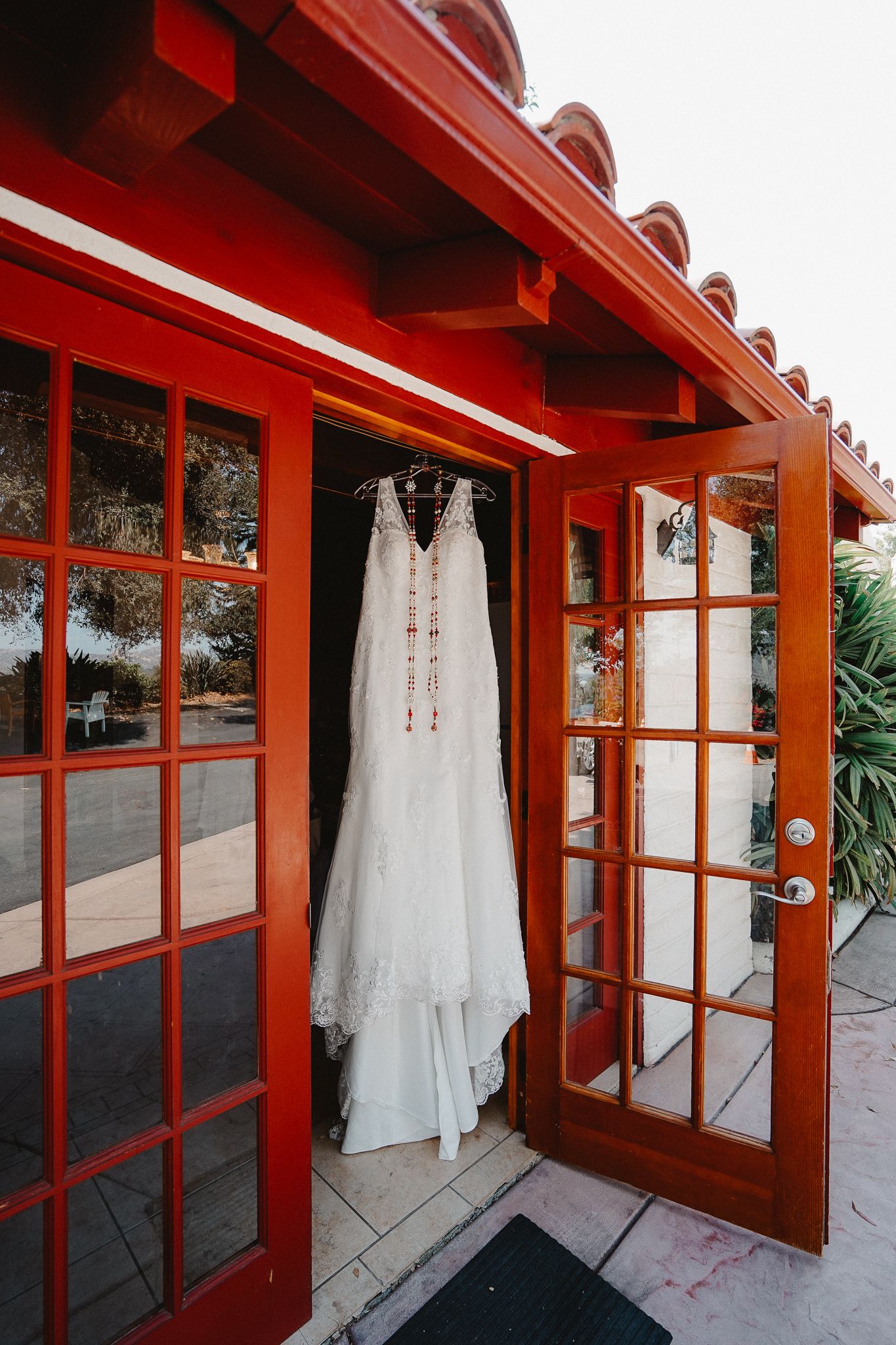 White wedding dress hanging on red Spanish-style building exterior.