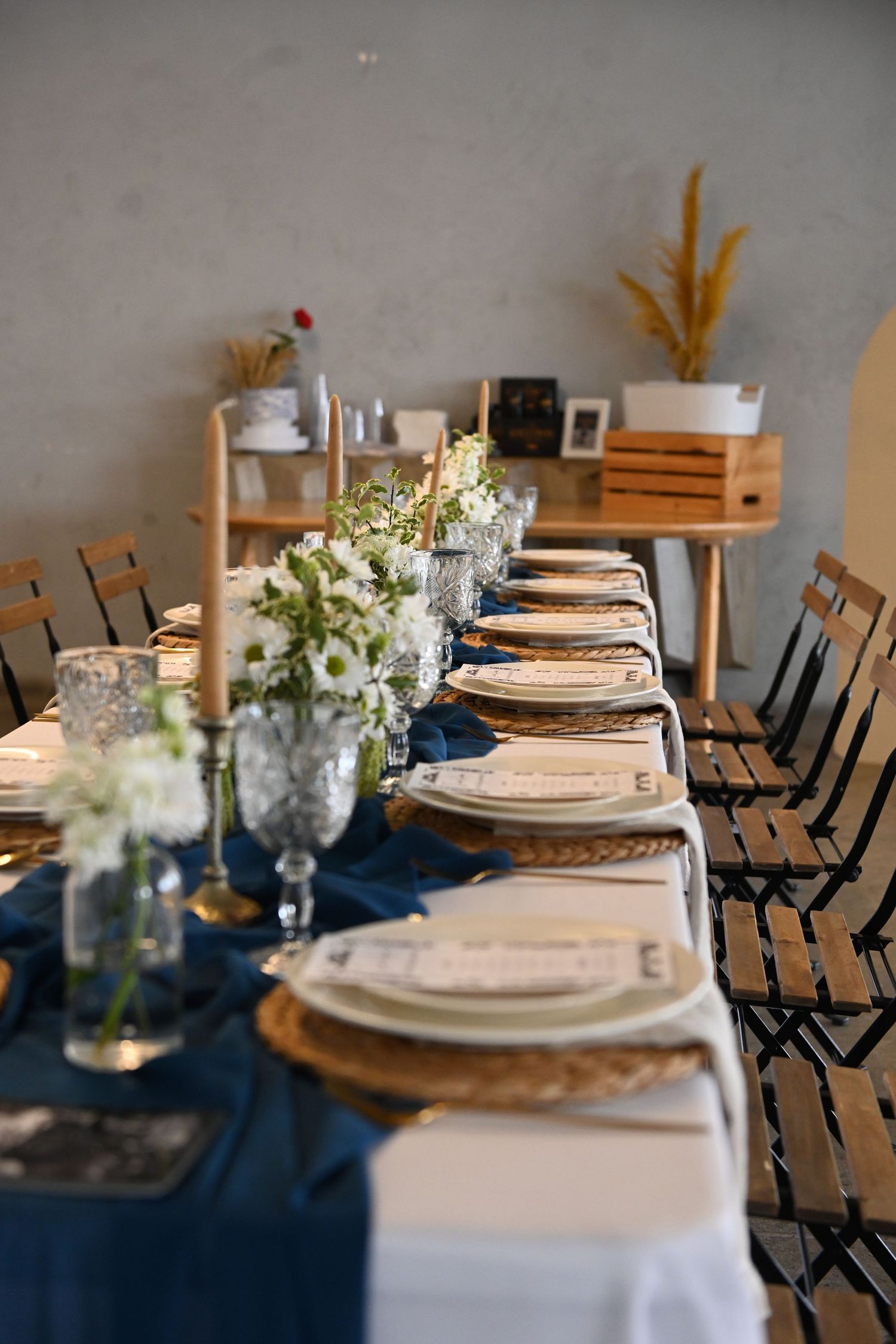 Elegant table setting with navy runner, white plates, and floral centerpieces.
