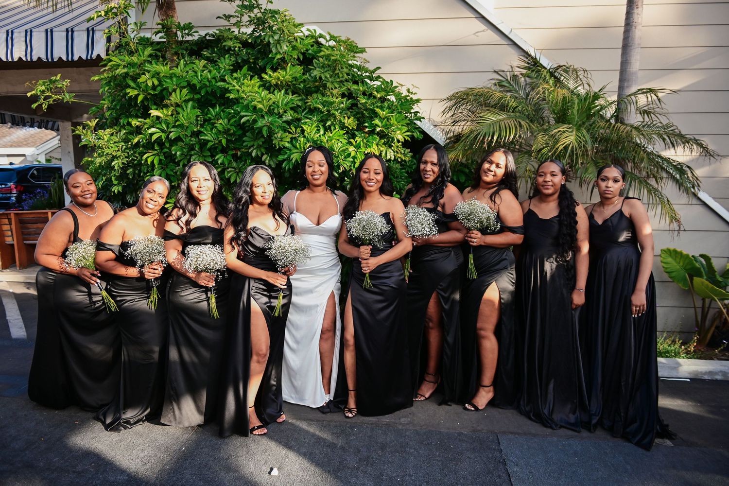 Wedding party poses outdoors in coordinating black dresses.