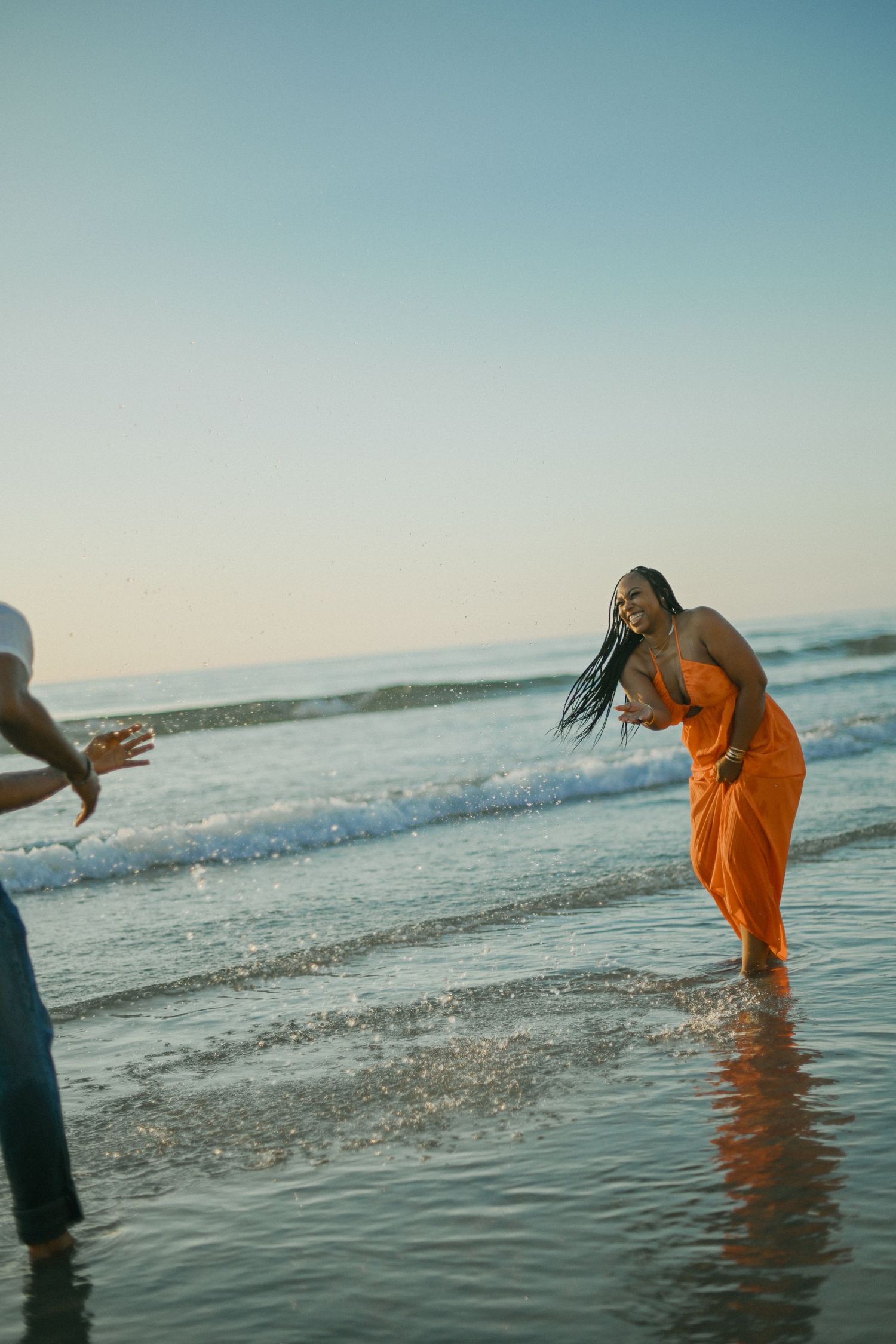 People playing and splashing in ocean waves during golden hour at the beach.